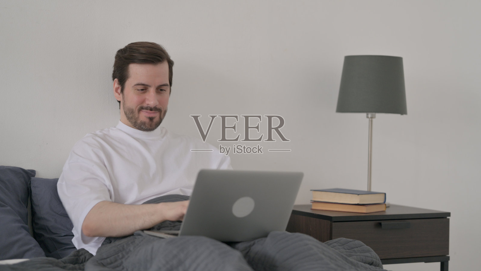 年轻人在床上用笔记本电脑工作照片摄影图片