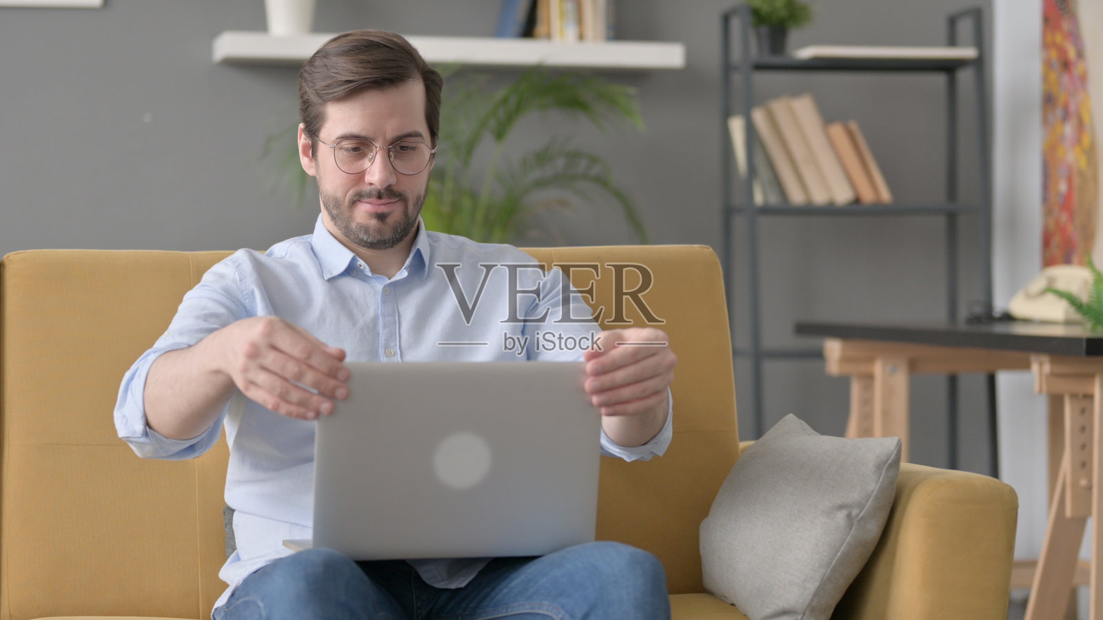 年轻人关上笔记本电脑，离开沙发照片摄影图片