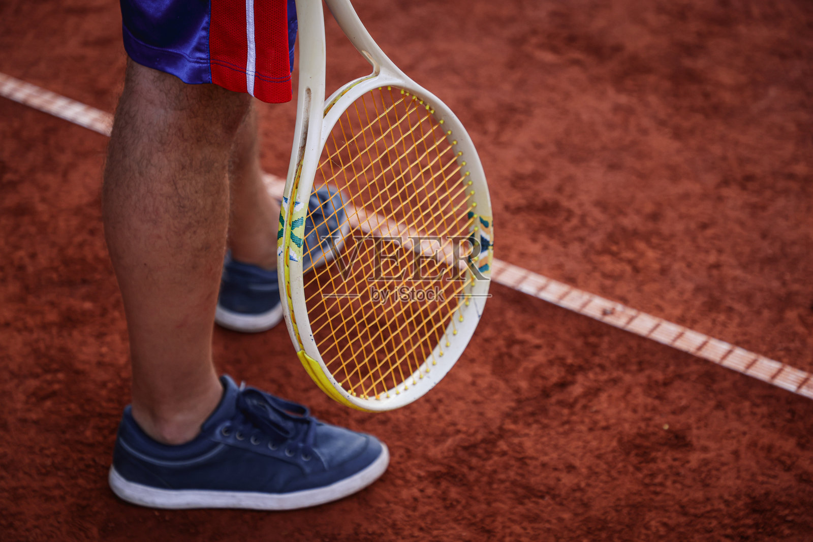 网球运动员站在网球场的发球线上，手持球拍照片摄影图片