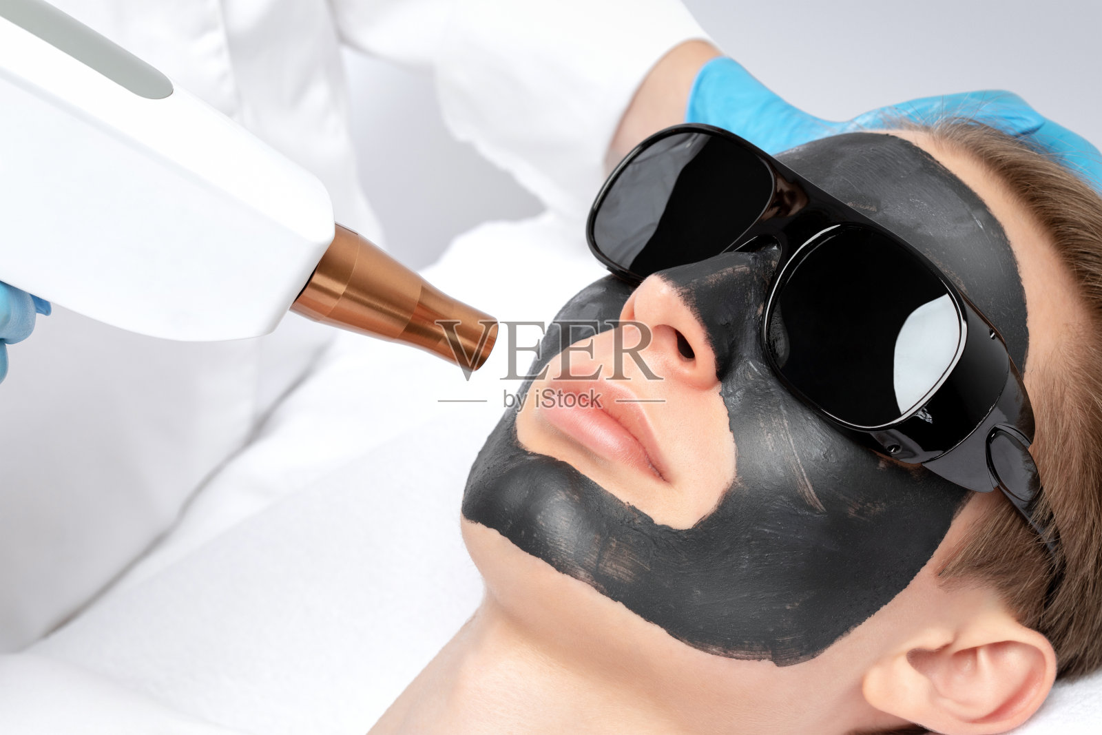 美容师在美容院给帅哥做脱碳手术。硬件男性美容。照片摄影图片