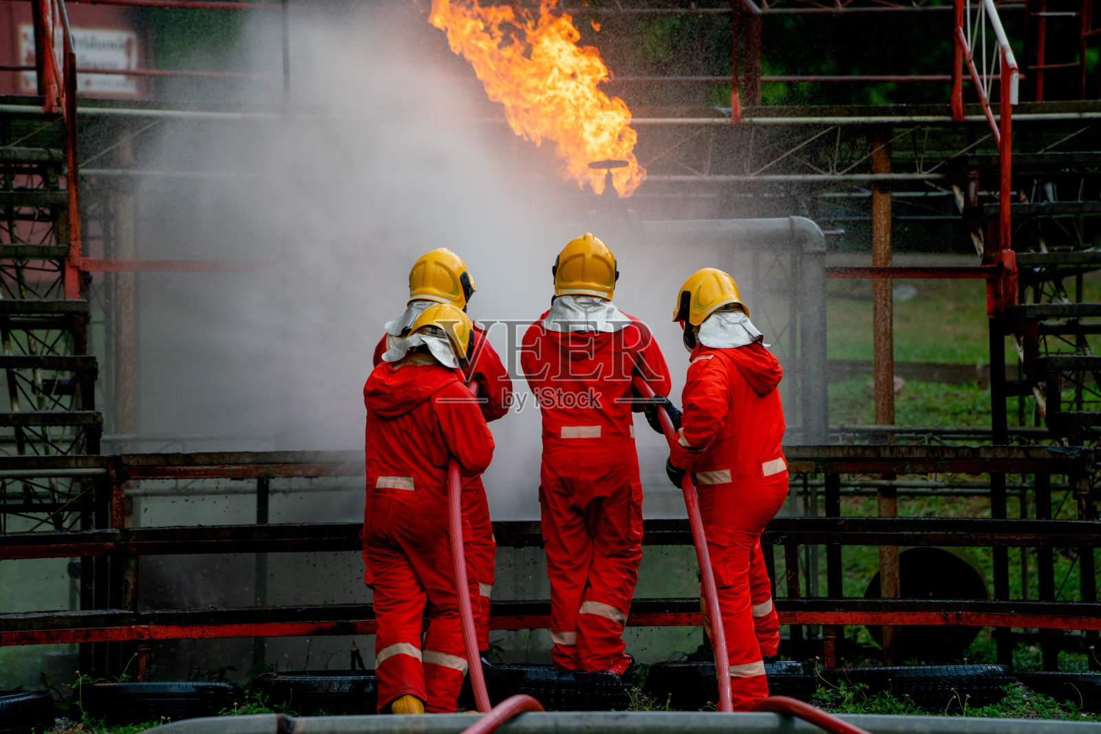 消防队员帮助和支持清除施工现场燃气管道的火灾，并使用水幕保护他们的队伍。照片摄影图片