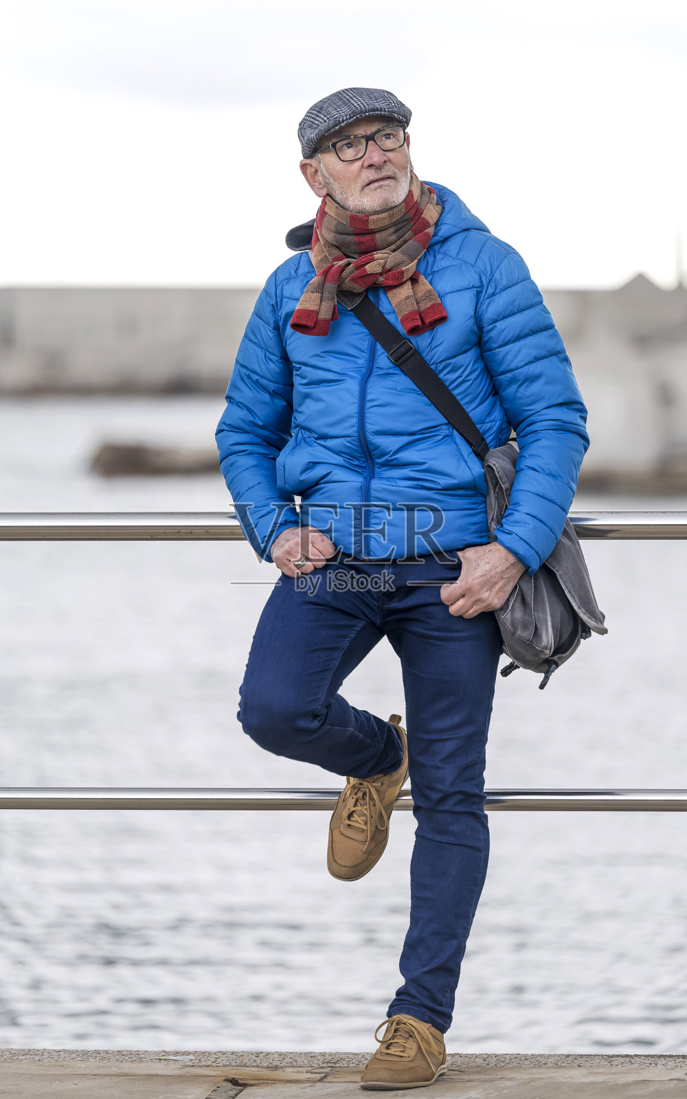 一位戴眼镜的老人靠在海边的栏杆上照片摄影图片