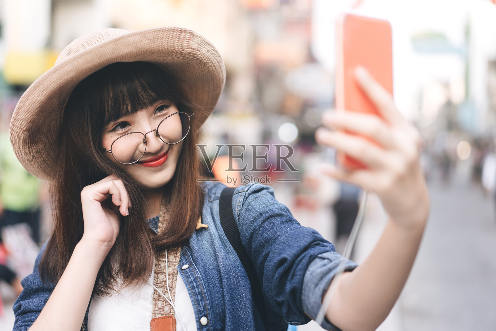 年轻的成年亚洲女性旅行者自拍的手机穿双肩包唐人街街头食品市场背景。照片摄影图片