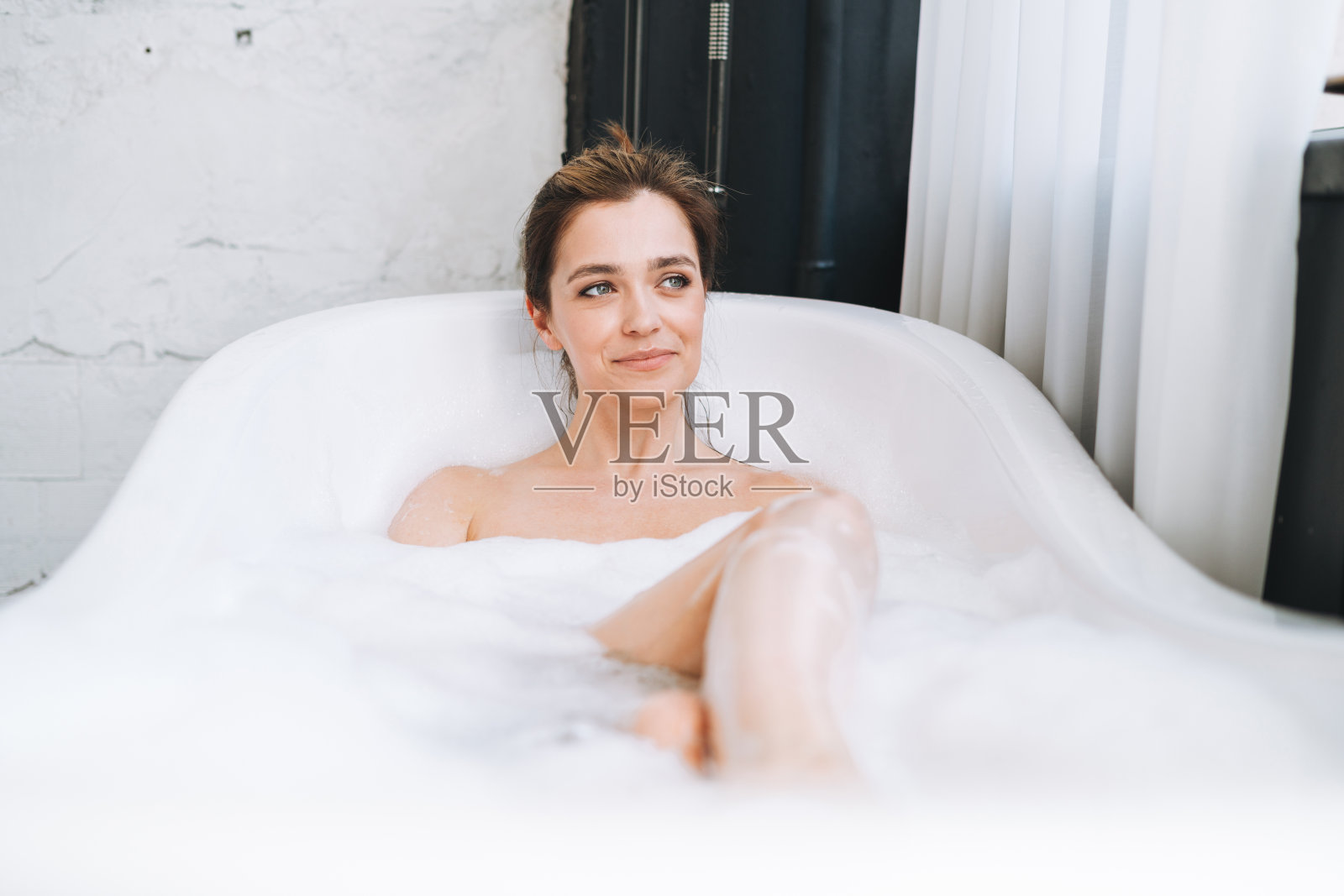 年轻快乐的女人在家用泡沫沐浴，犒赏自己照片摄影图片