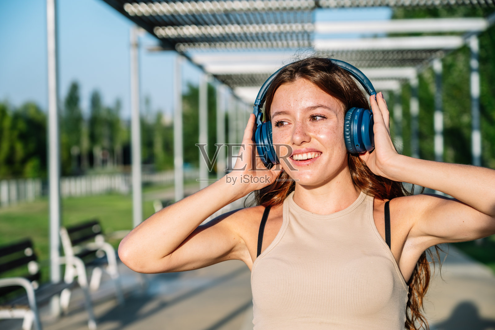 快乐的女人在公园里戴着耳机听音乐照片摄影图片