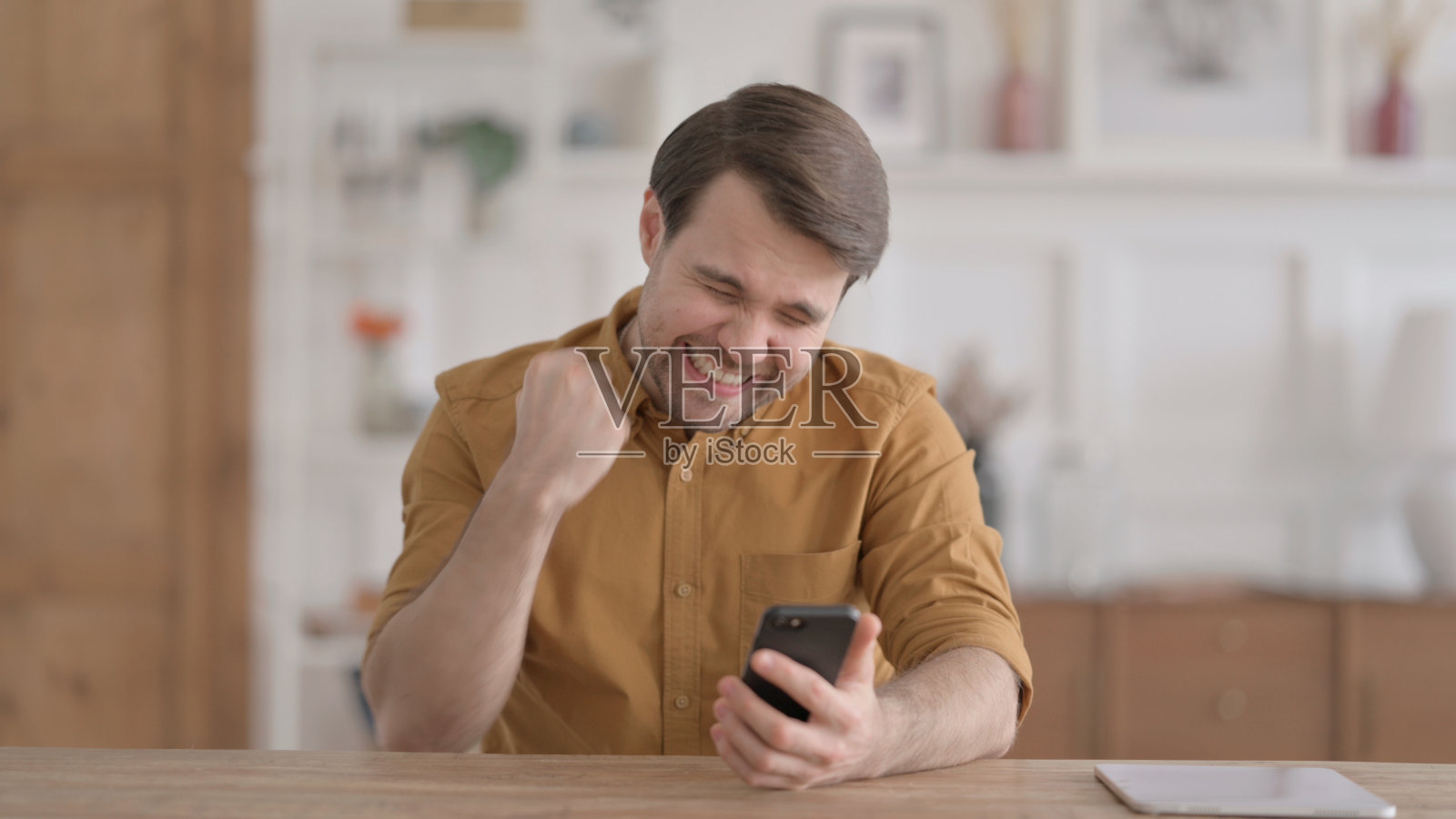 成功的年轻人用智能手机庆祝照片摄影图片