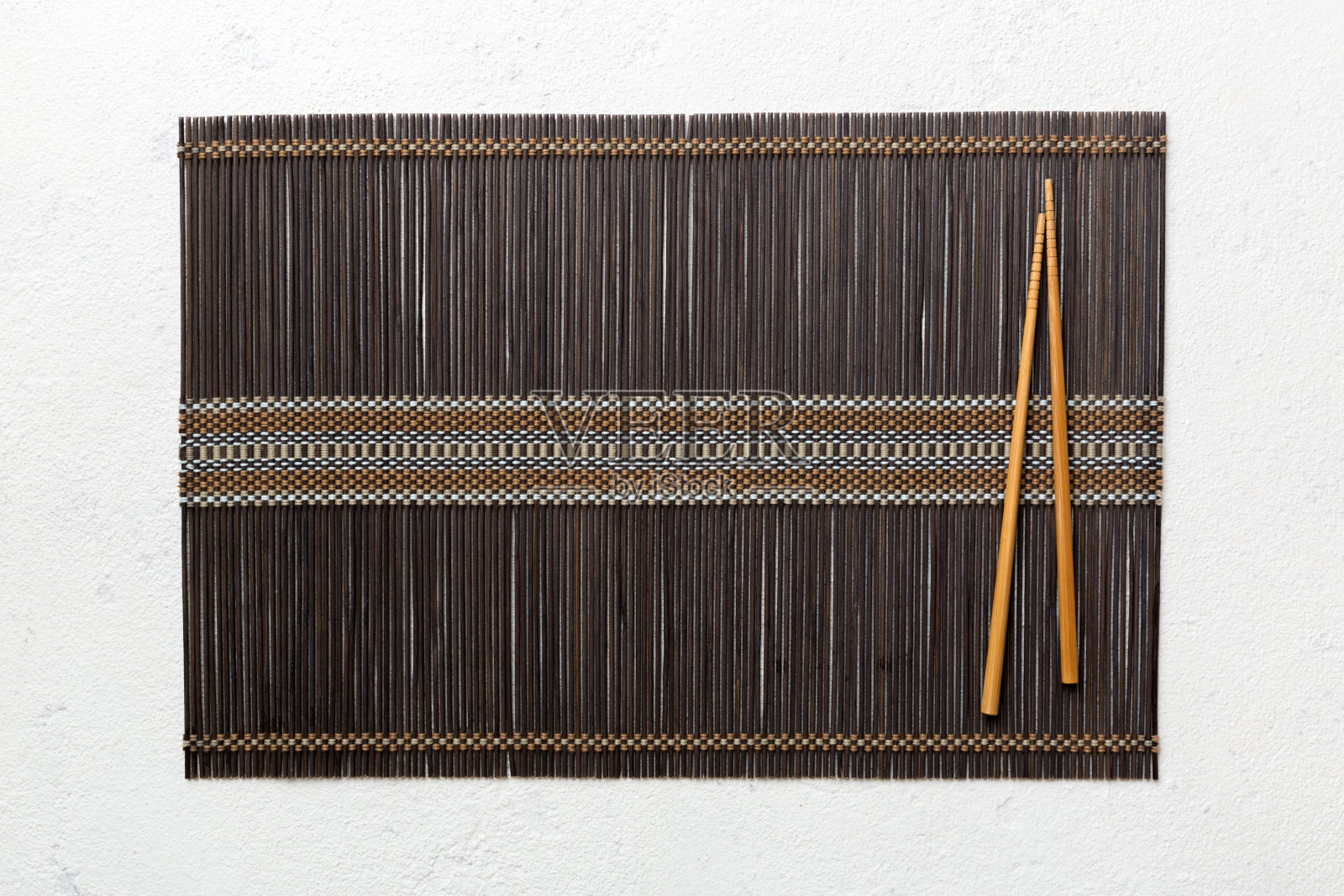 两根筷子和水泥背景上的竹席。俯视图，复制空间照片摄影图片