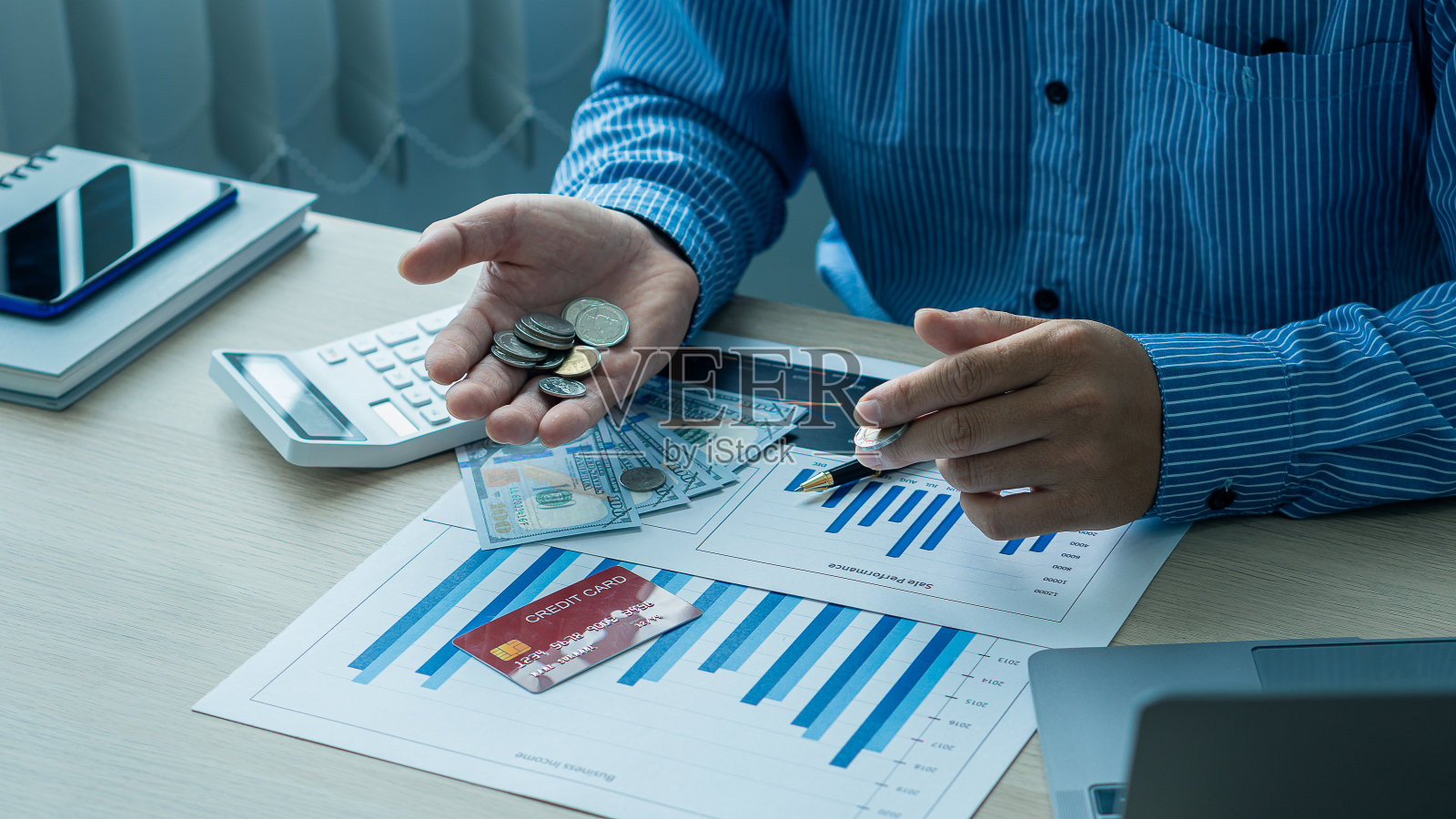 商人拿着笔和笔记本电脑绘图文件金融计算器甲板进行计算和分析照片摄影图片