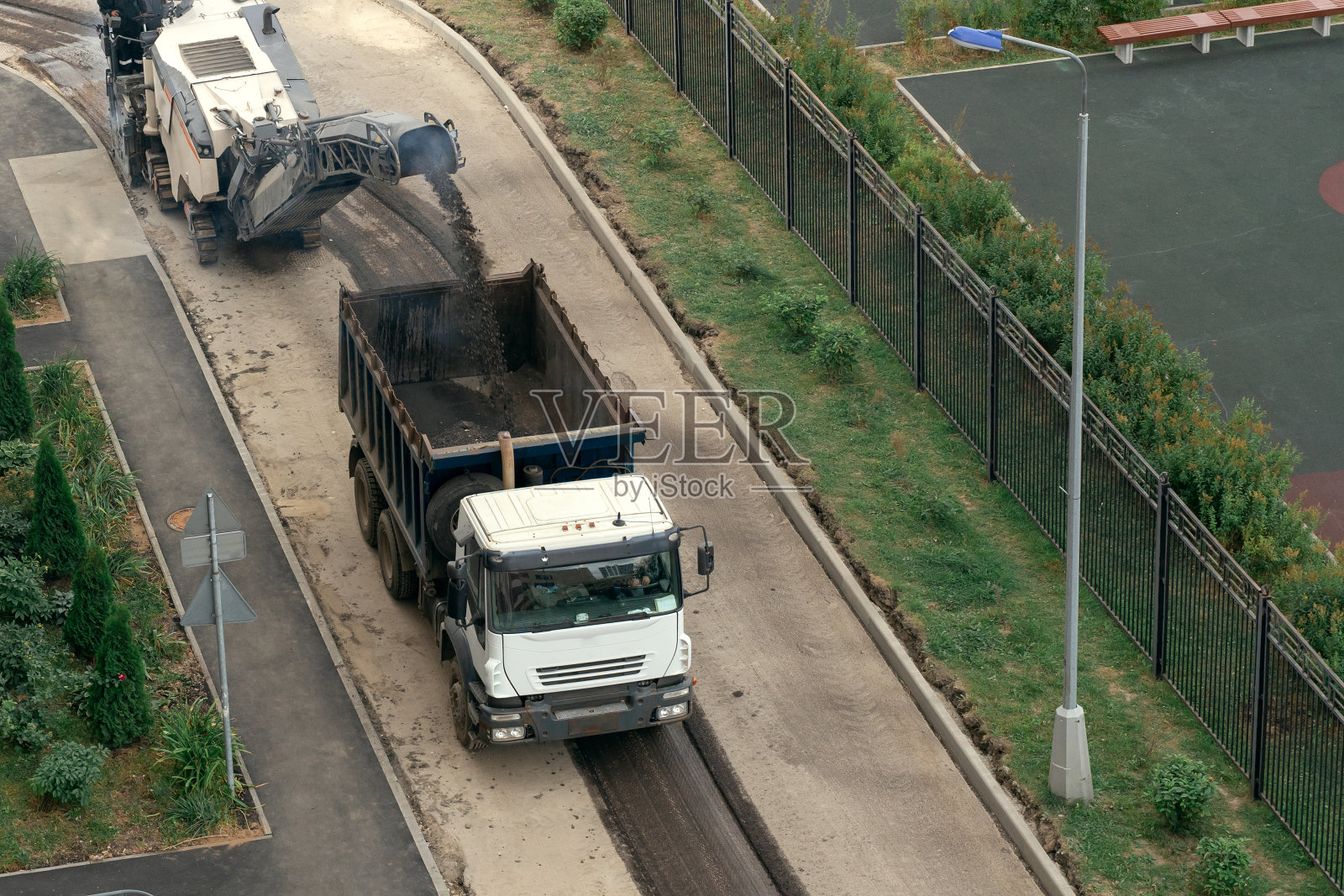沥青碾磨机在街道上工作。照片摄影图片