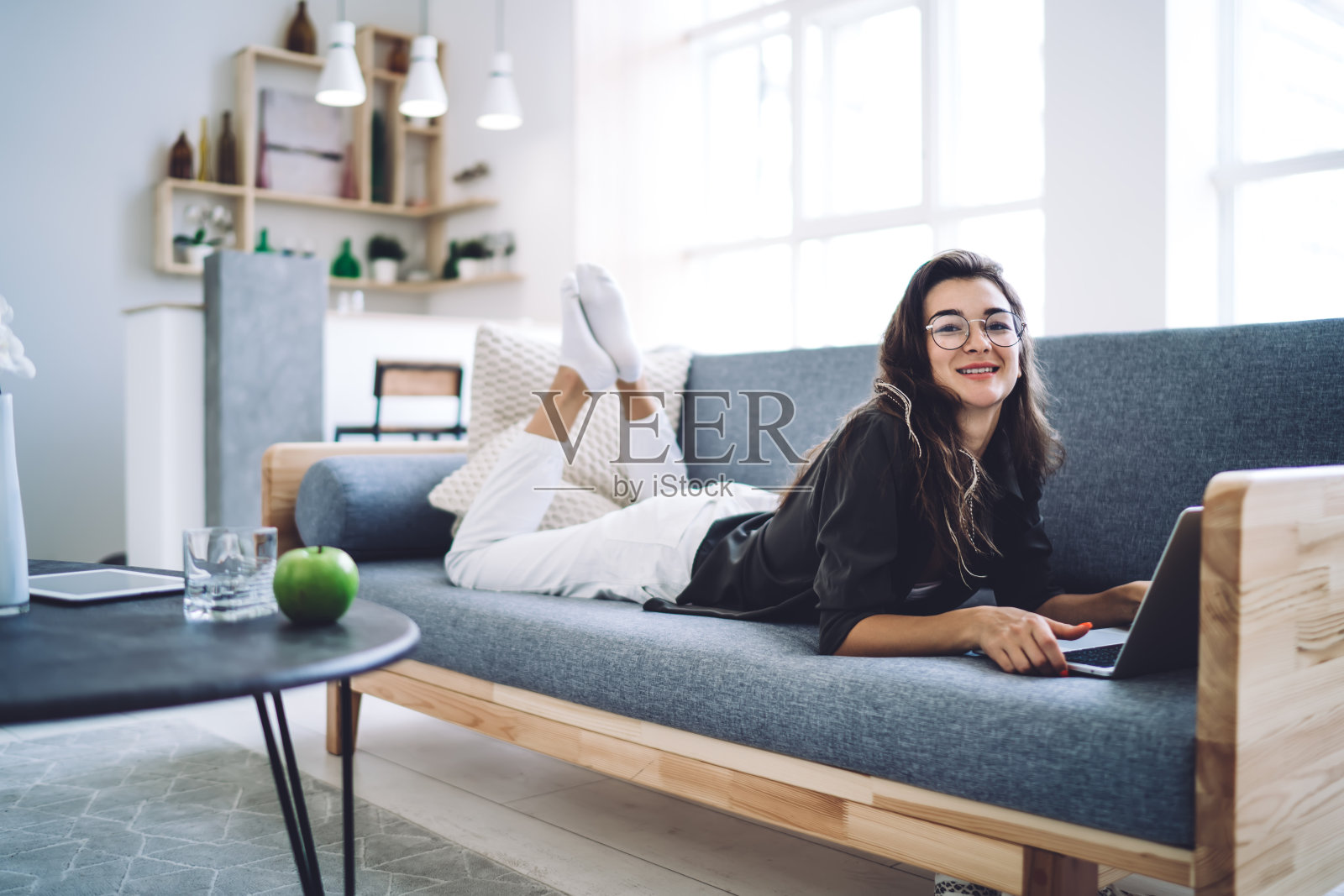 快乐的女学生在沙发上休息，带着笔记本电脑照片摄影图片