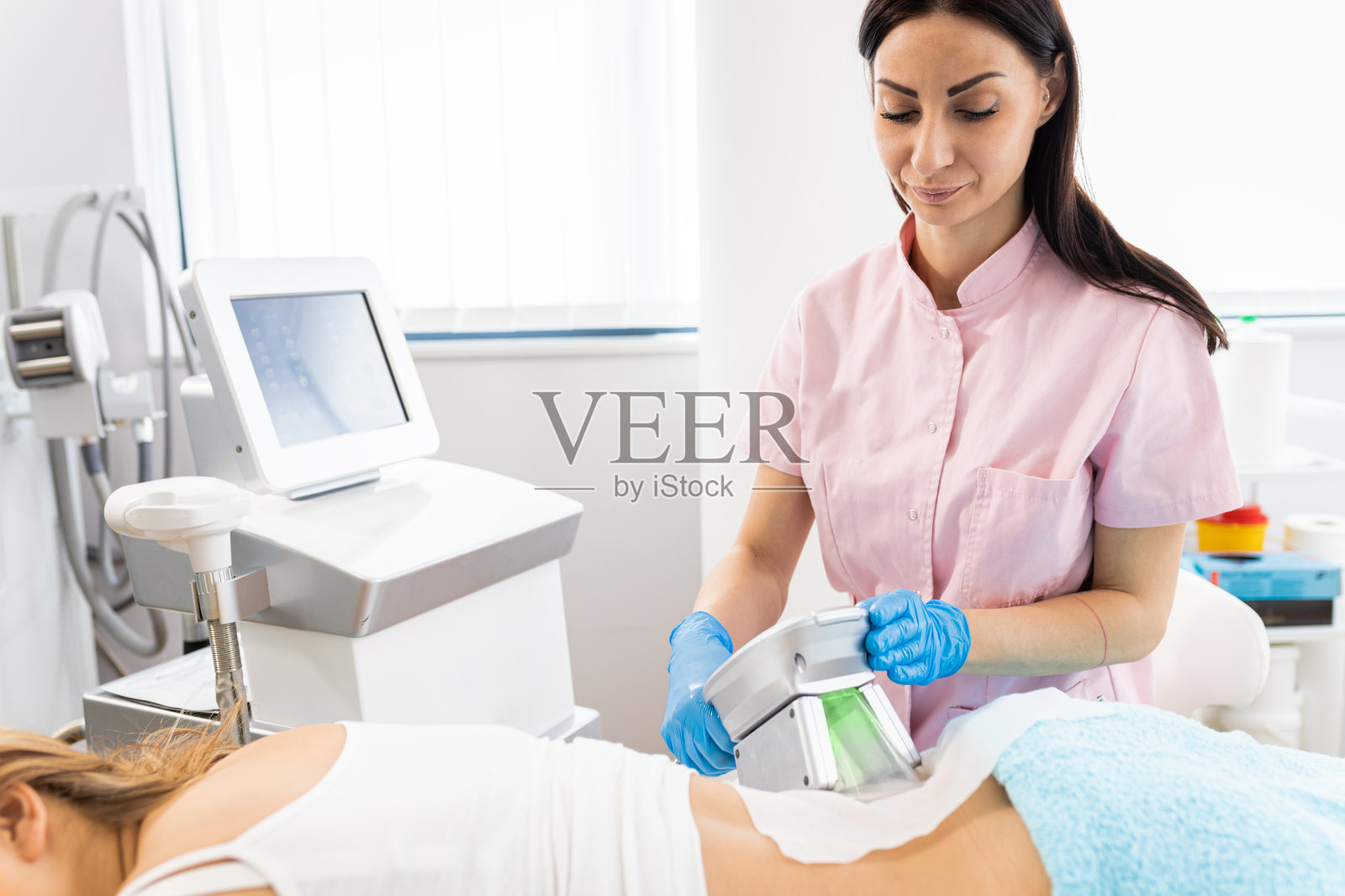 美容师在美容院应用低温溶脂治疗。照片摄影图片