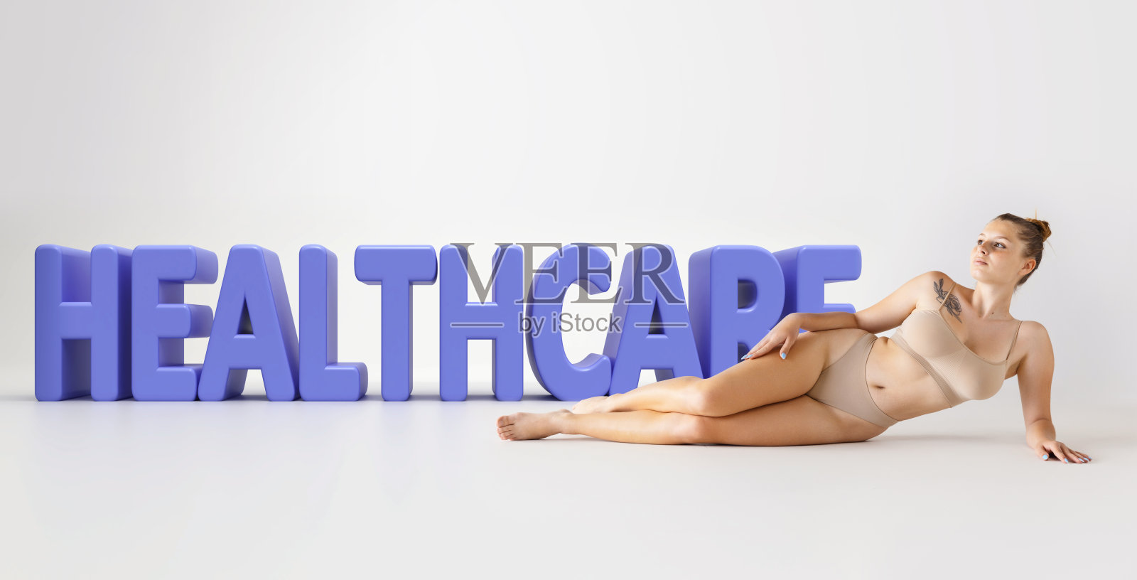 画像温柔的年轻女子躺在地板上米色内衣在3D医疗保健字母在灰色背景照片摄影图片