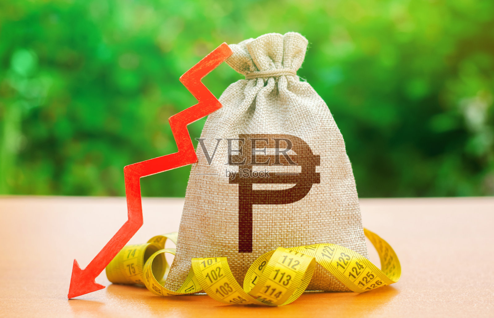 菲律宾比索钱袋下箭头和卷尺。资本外流。工资和福利下降。工资减少，社会福利减少。削减成本。国家银行降低贴现率照片摄影图片