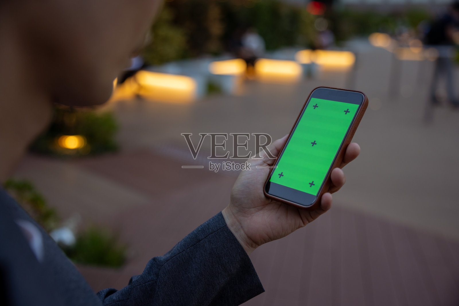 黄昏时分，一名男子在城市里看智能手机屏幕照片摄影图片