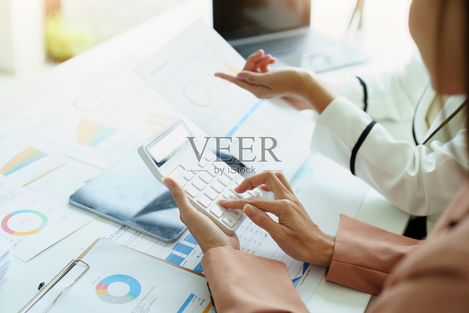 两个亚洲女商人使用计算器和文件工作。照片摄影图片