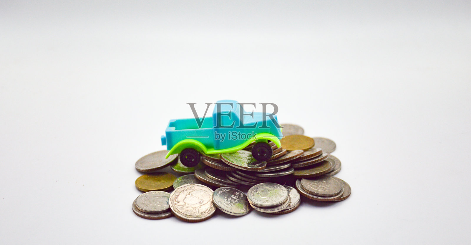 蓝绿色的小货车，白色背景上有一堆硬币照片摄影图片