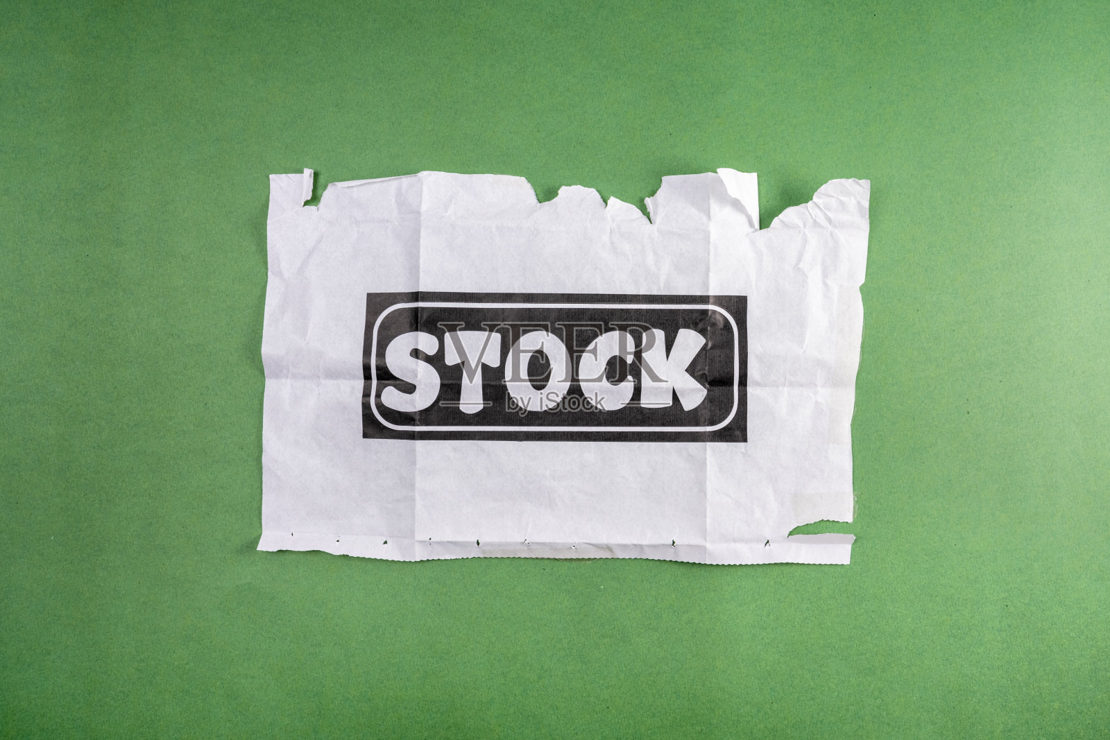 字库。股票摄影的概念。折叠的白纸，上面印着“股票”两个字。绿色背景。照片摄影图片