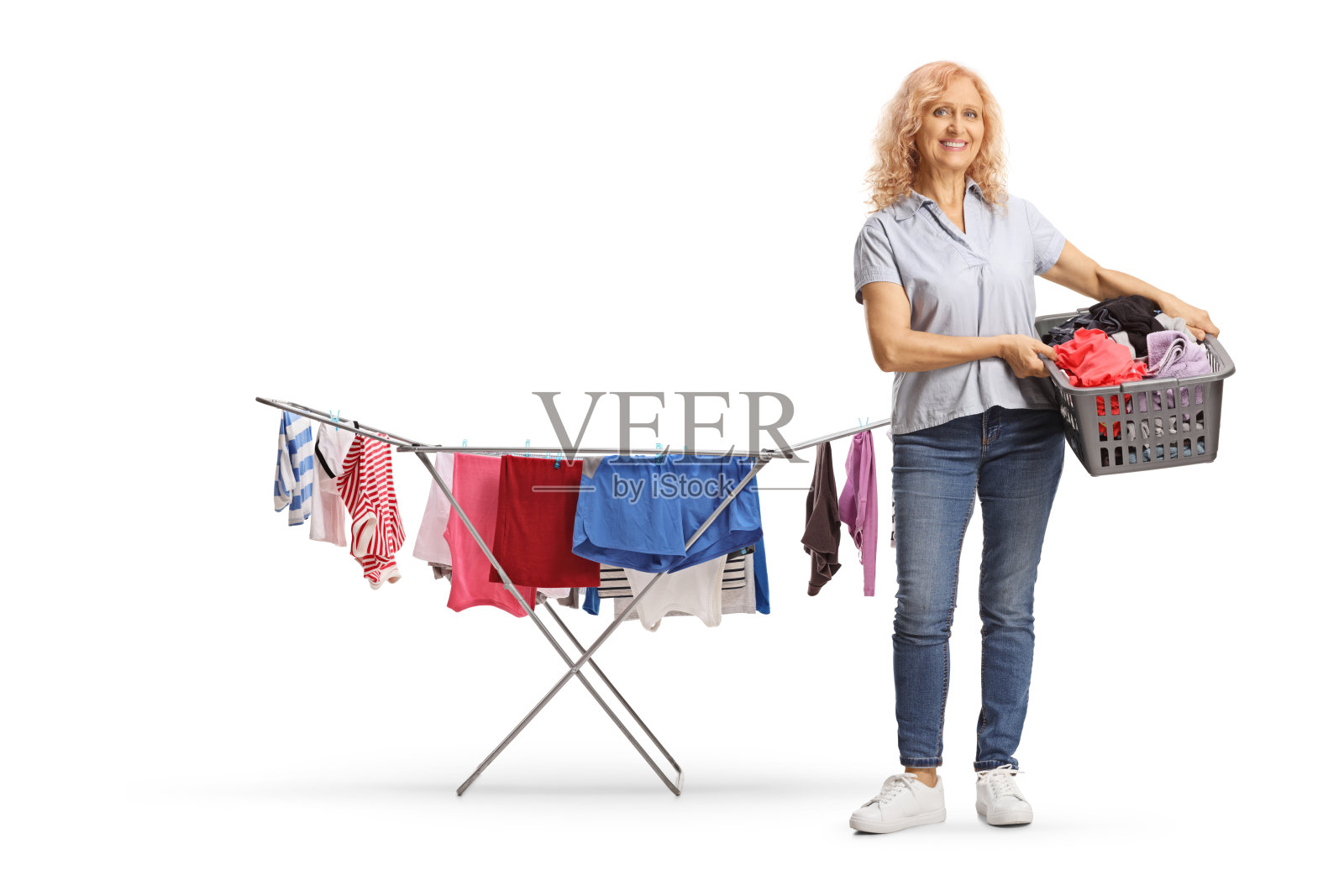 一个女人的完整长度肖像与洗衣篮站在旁边的晾衣架的衣服照片摄影图片