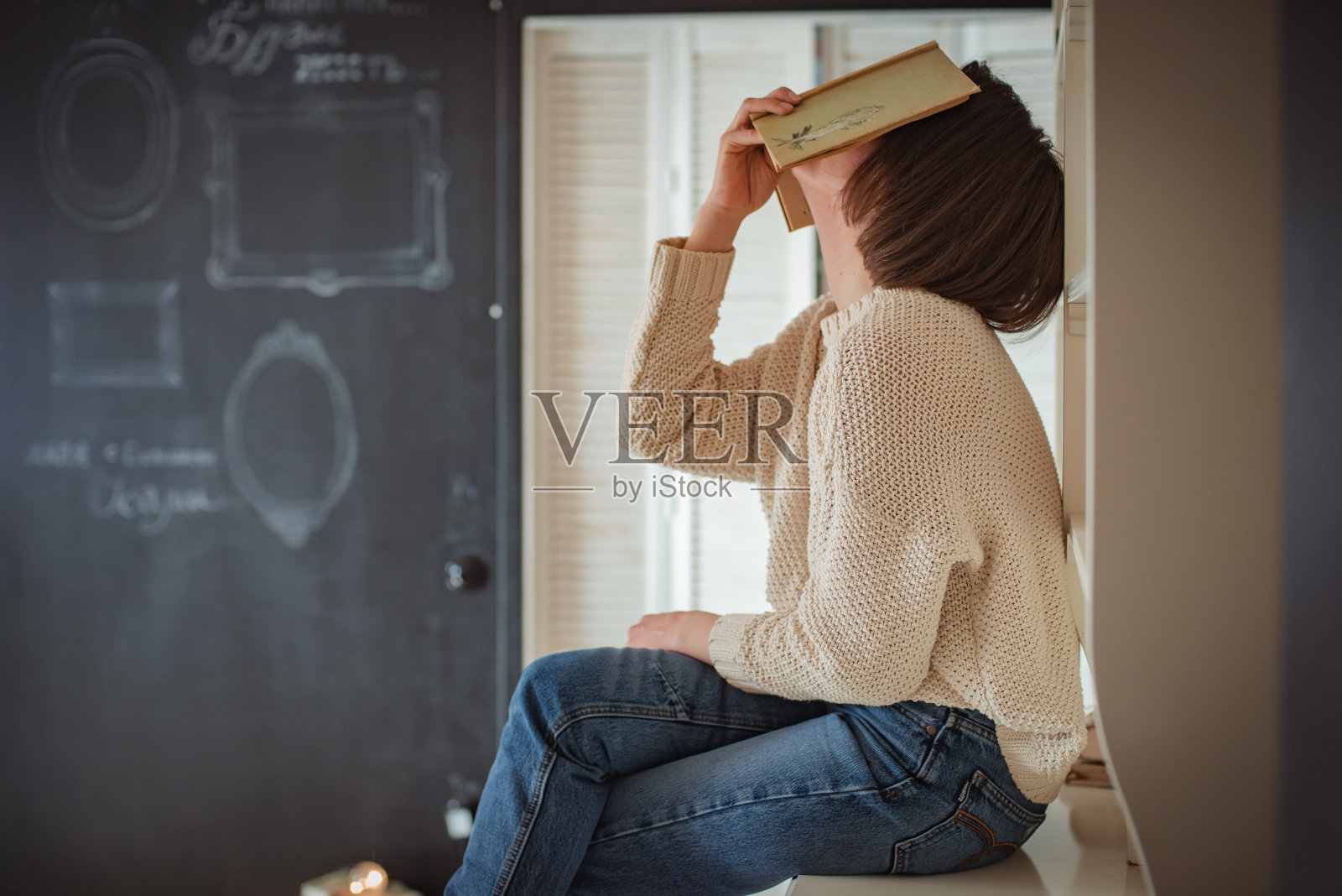 美丽的年轻女子在家附近看书照片摄影图片