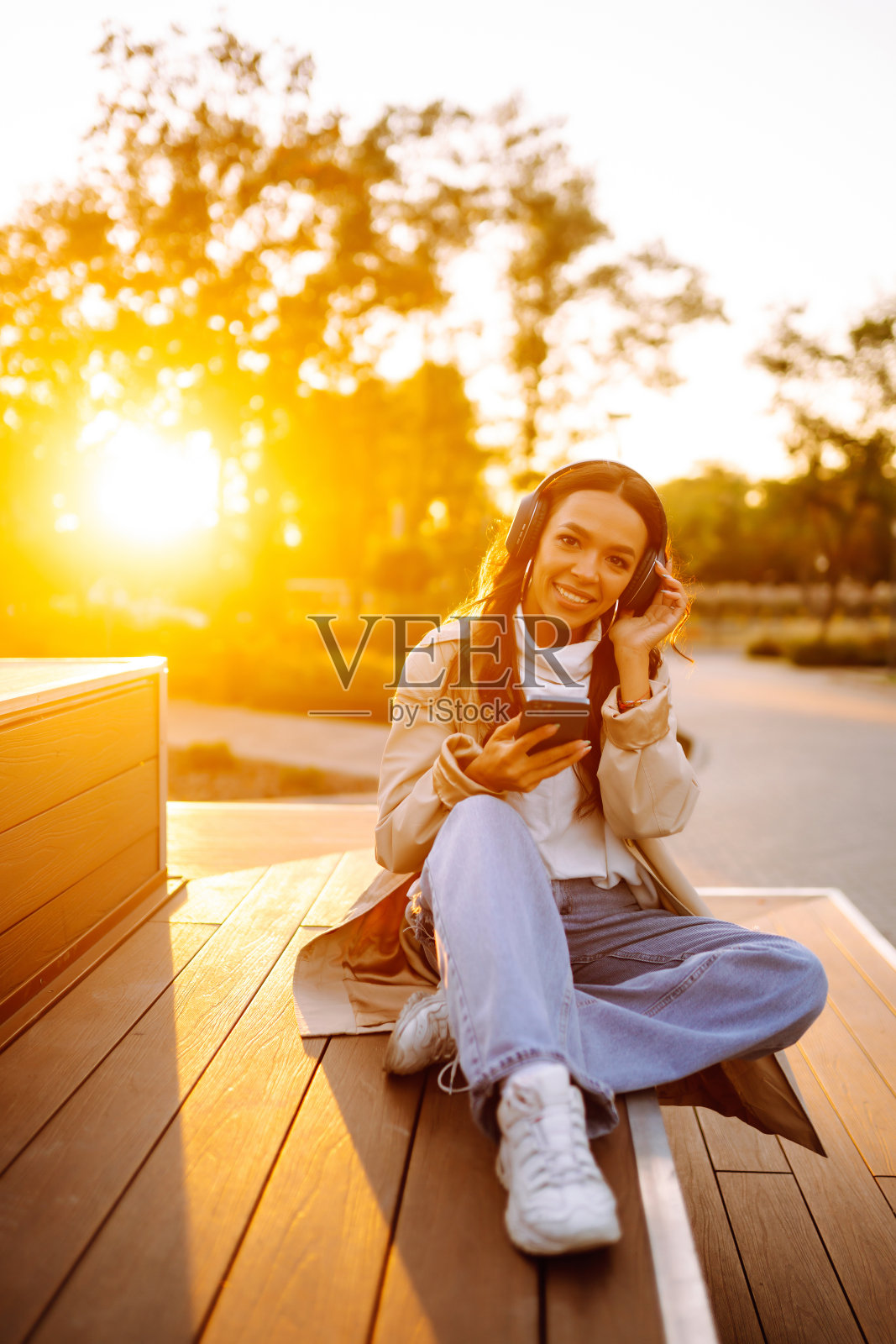 年轻女子在户外戴着耳机听音乐。照片摄影图片