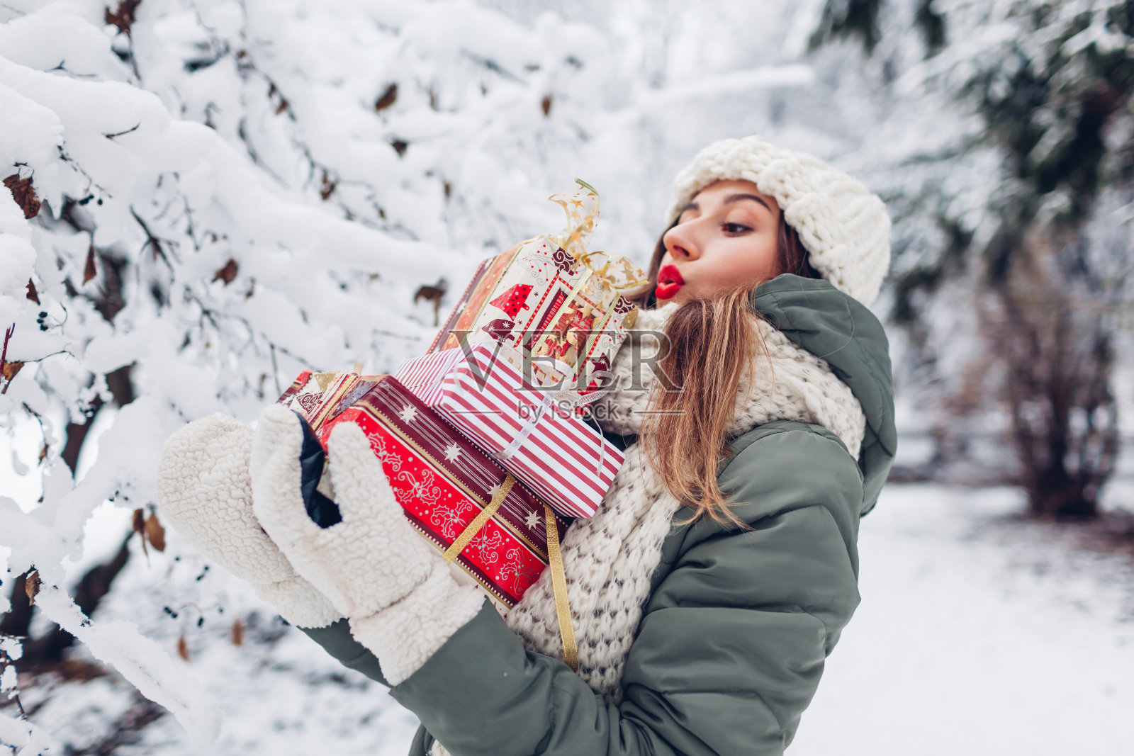 在下雪的冬天公园里，年轻的女人拿着成堆的圣诞礼物礼品盒。喜庆的节日照片摄影图片