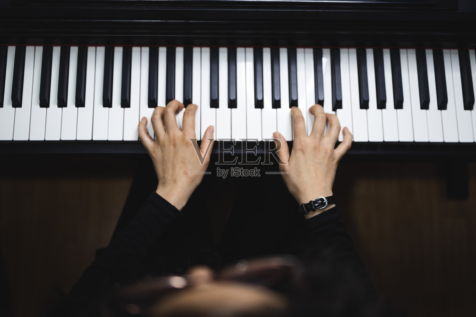 俯视图的妇女的手弹钢琴阅读乐谱。照片摄影图片