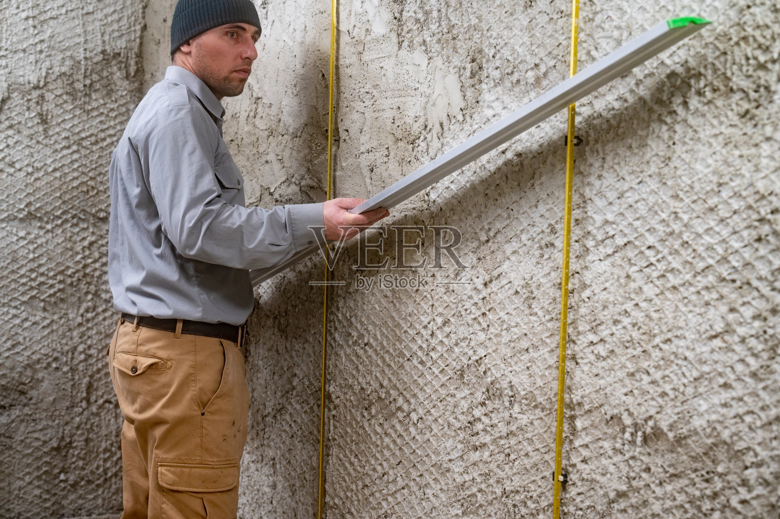 金属引导信标附在墙上，主人检查信标是否符合平面规则。照片摄影图片