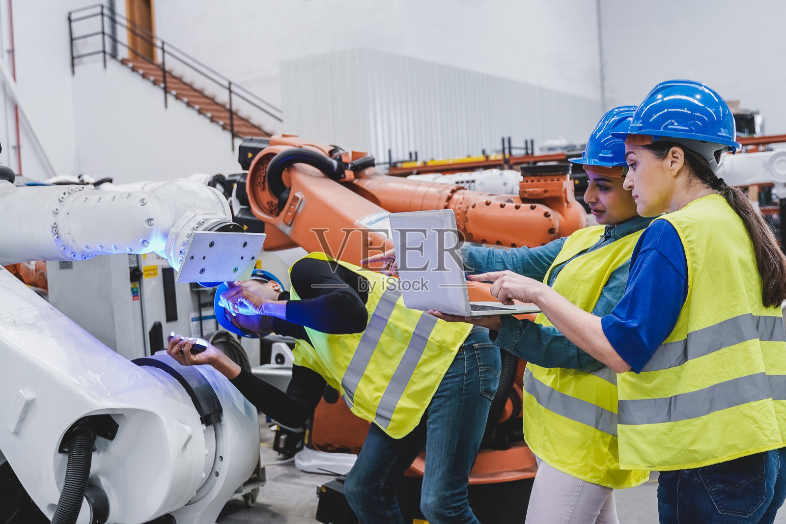 在自动化和机器人设施内研究机器人的多种族工程师-新的工业技术概念照片摄影图片