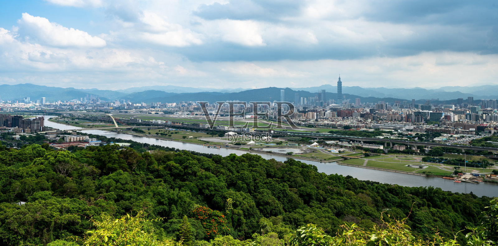 在一个多云的日子，在台湾台北市，从山间小径，穿过森林，俯瞰台北市和河流。照片摄影图片