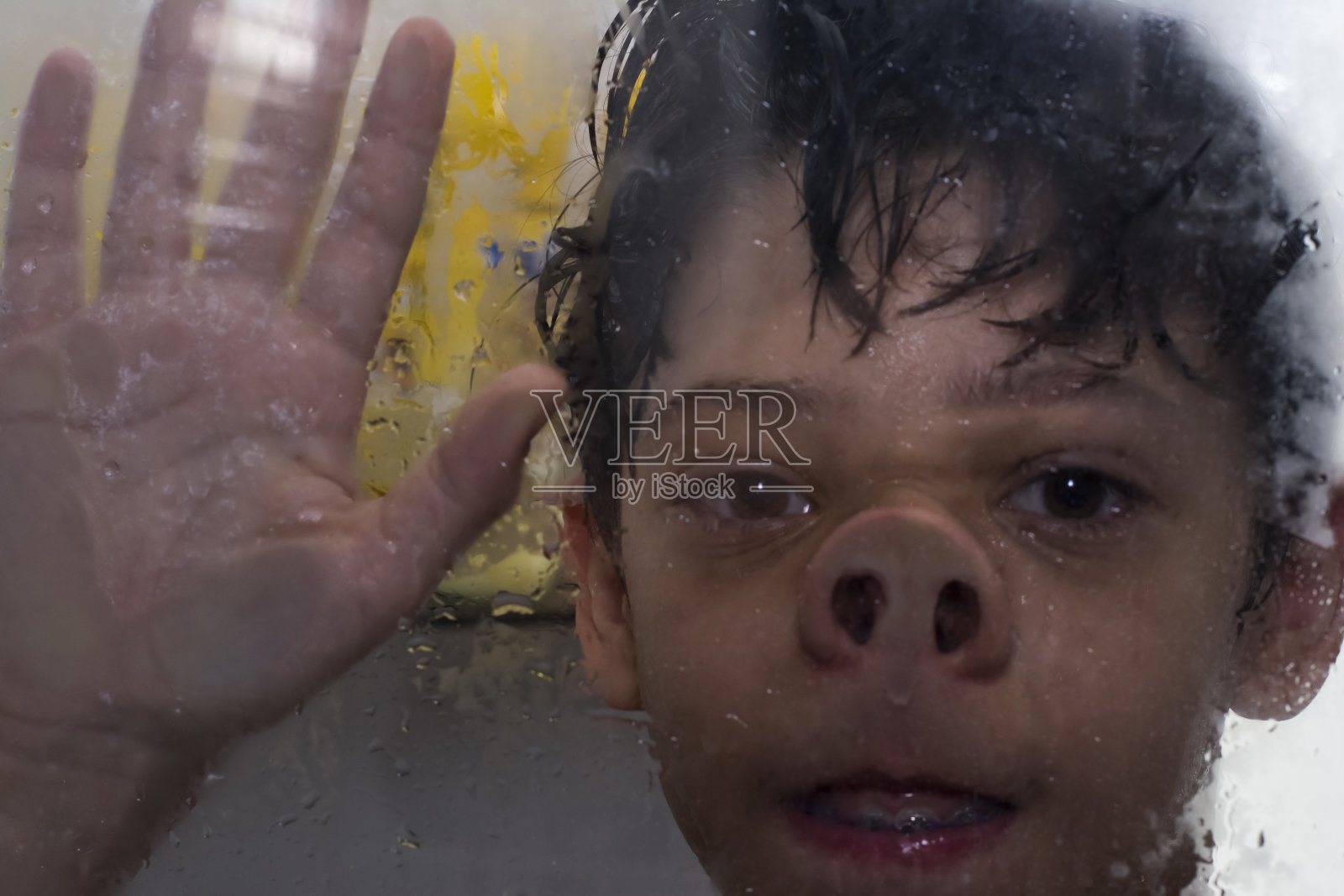 有趣而快乐的男孩站在流水下享受着沐浴。照片摄影图片