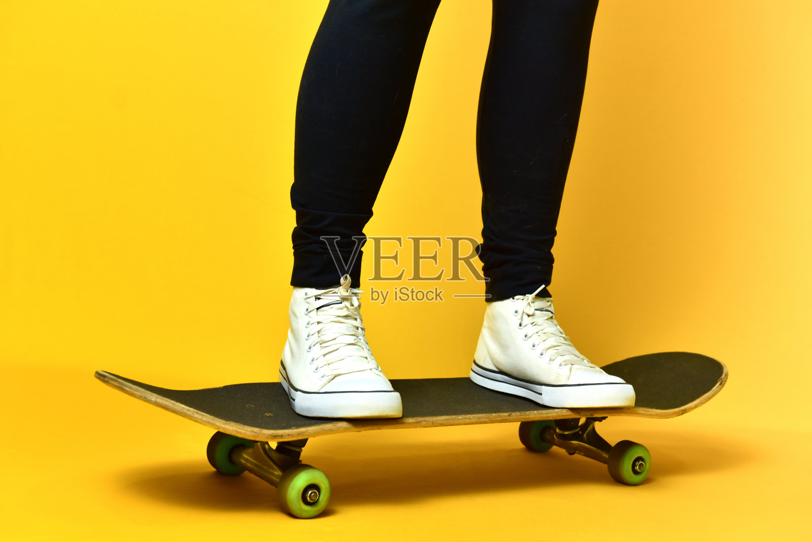 滑冰女孩的腿穿着白色运动鞋在黄色的背景。照片摄影图片