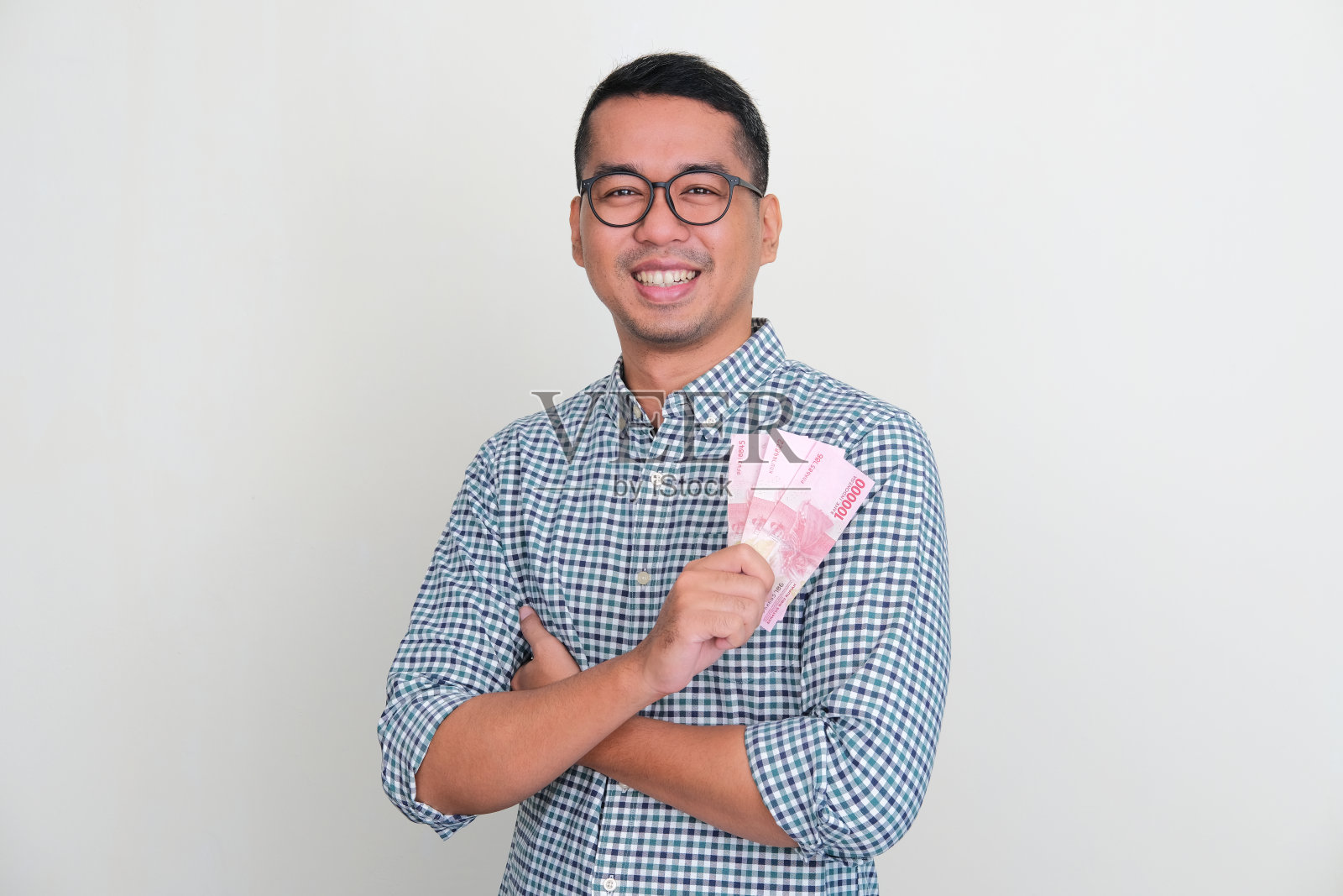 亚洲男子对着镜头微笑，双臂交叉，展示着金钱照片摄影图片