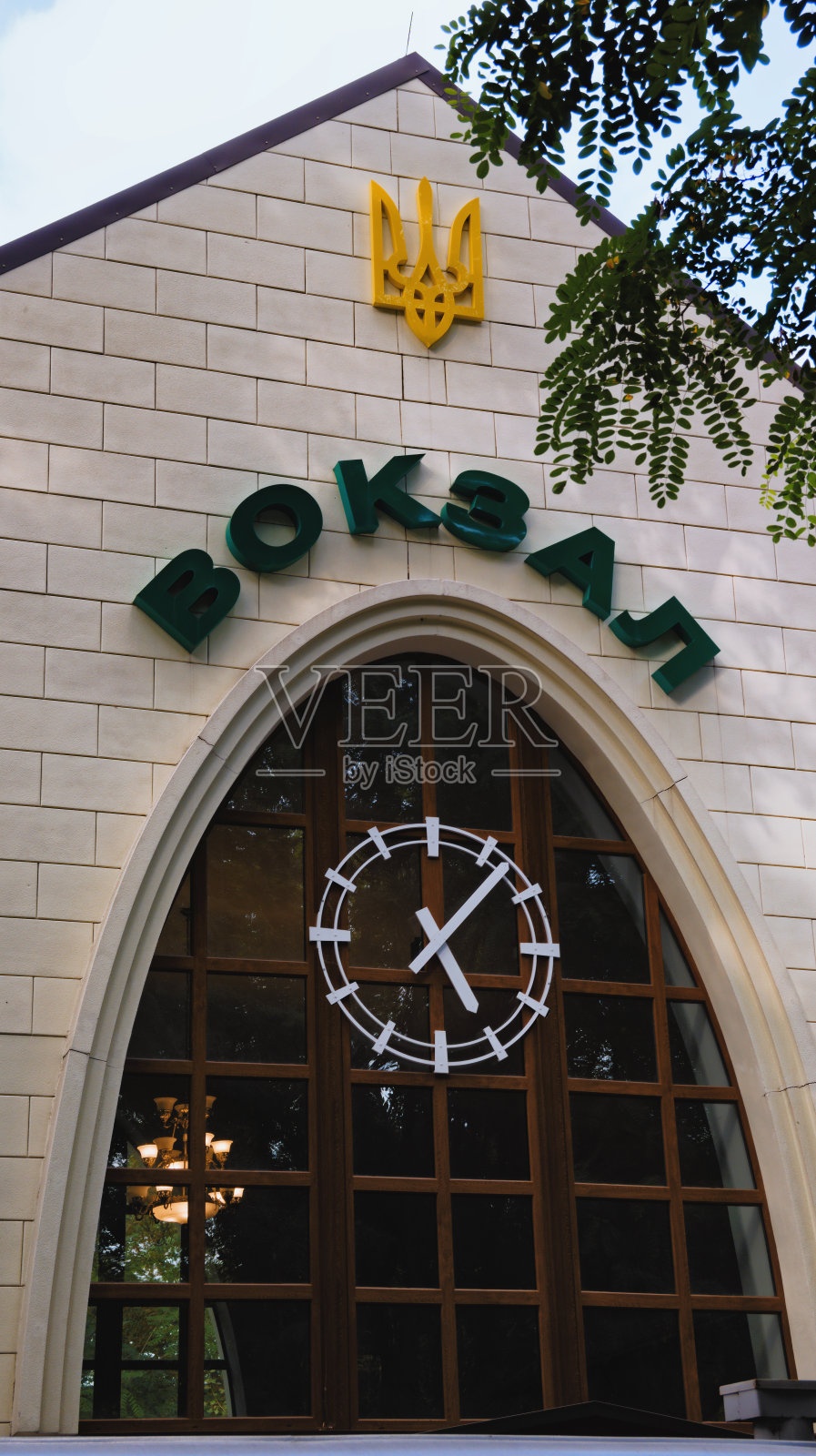 火车站正面的上部有乌克兰语的Vokzal(英语:station)和现代时钟。高角度的观点。树叶边界。Syretsky公园的基辅儿童铁路照片摄影图片