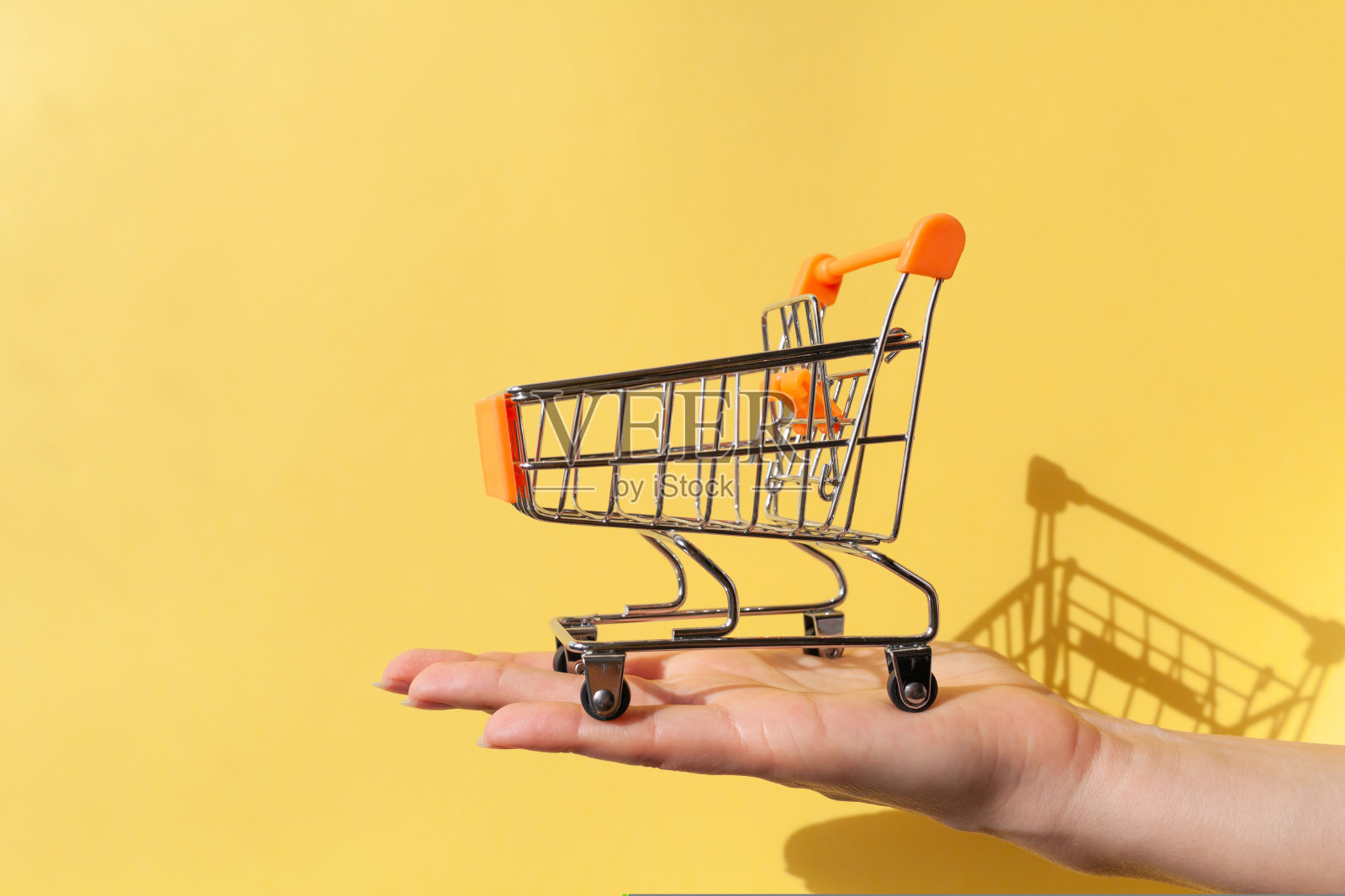 一位女士手里拿着一个超市里的小空金属手推车照片摄影图片