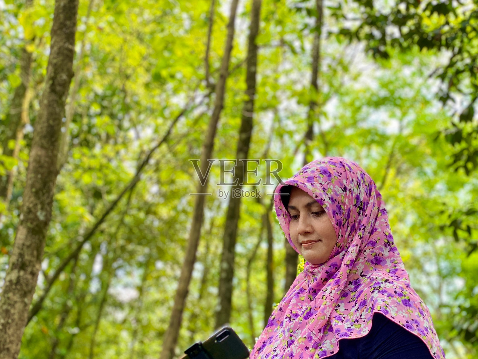 喜欢摄影的戴着头巾的女子在城市森林里用智能手机看照片照片摄影图片