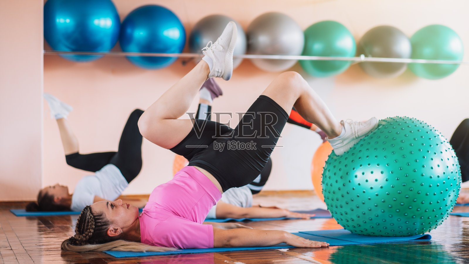 一群用健身球躺在垫子上健身的妇女照片摄影图片