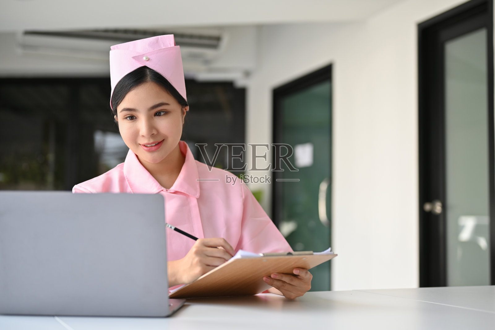 美丽的亚洲女护士在她的制服在她的办公桌上工作。照片摄影图片