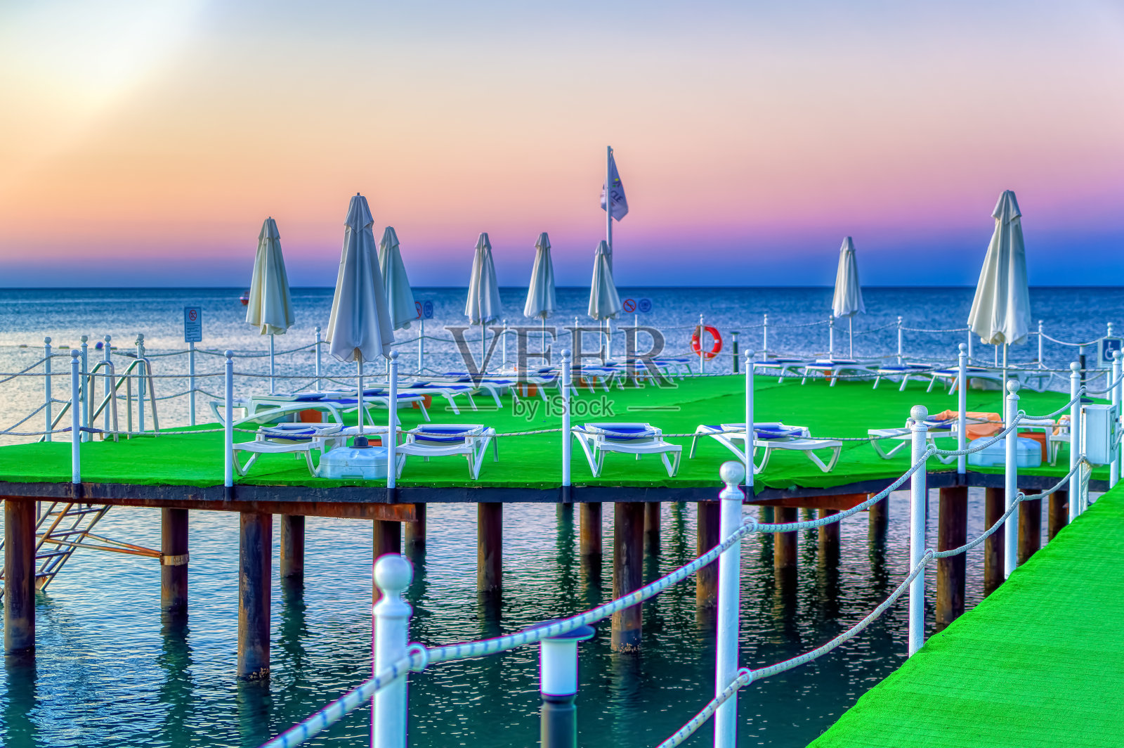 夏日清晨，空旷的沙滩上有日光浴床和遮阳板。照片摄影图片