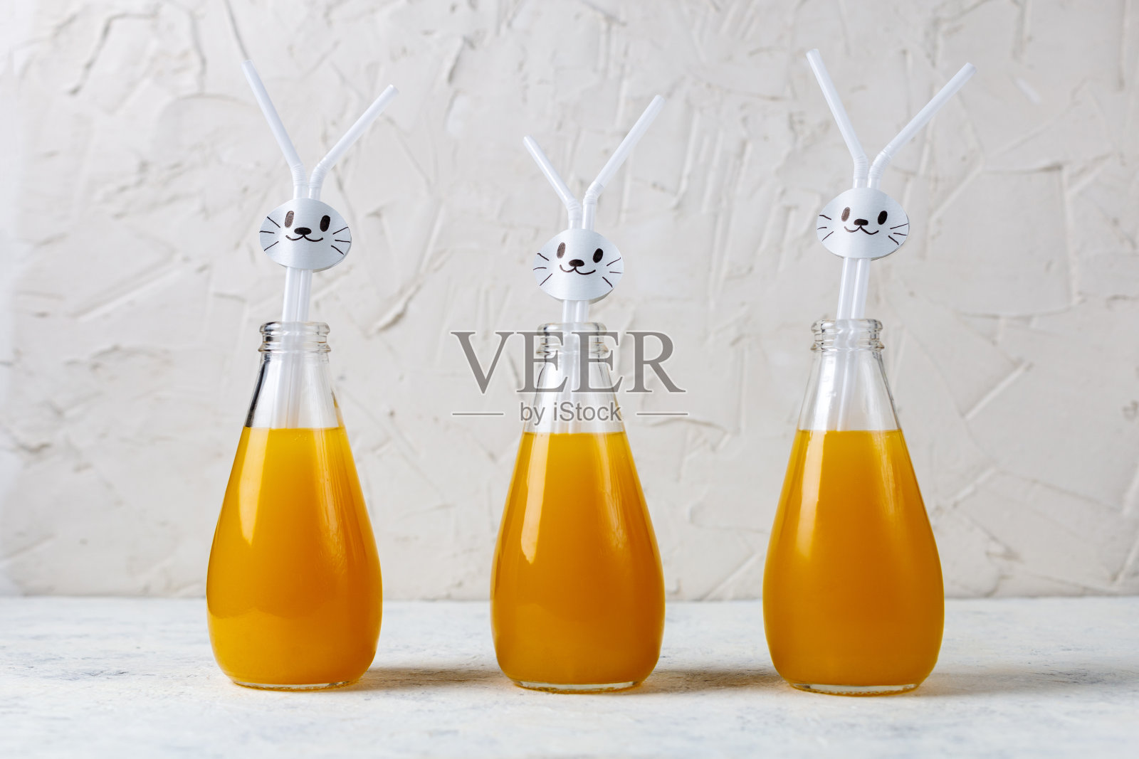 儿童派对的橙汁饮料，以白兔为背景装饰。照片摄影图片