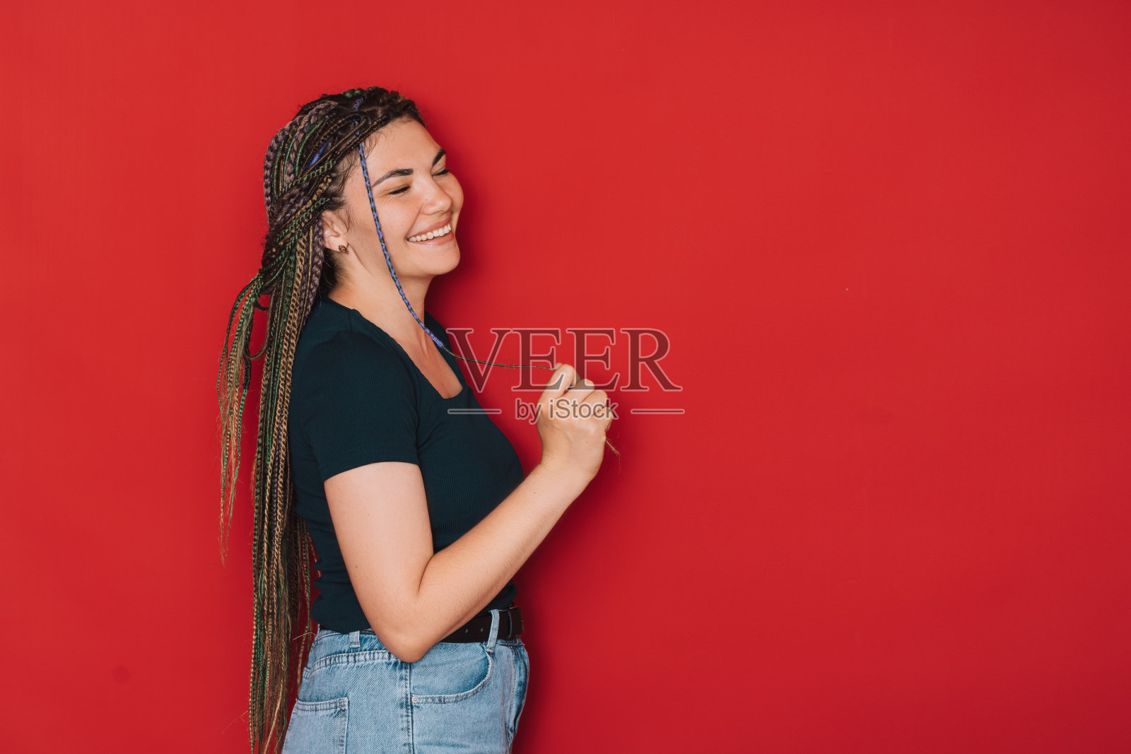 女孩在红色背景下梳着五颜六色的辫子微笑照片摄影图片