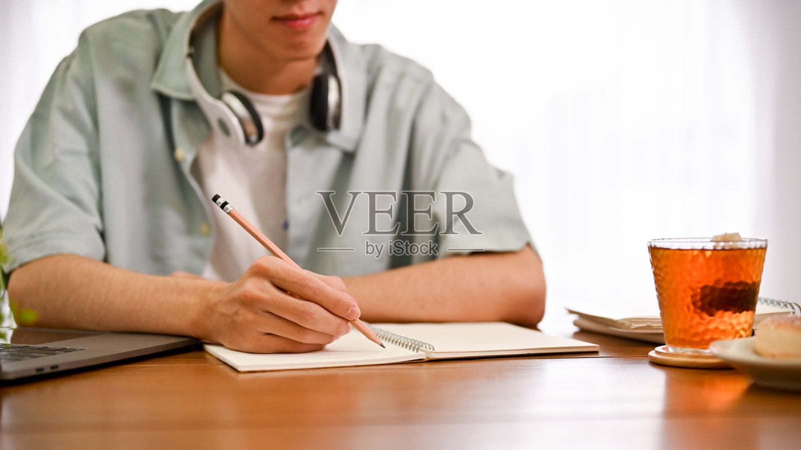 聪明的年轻亚裔男大学生在做作业。裁剪图像照片摄影图片