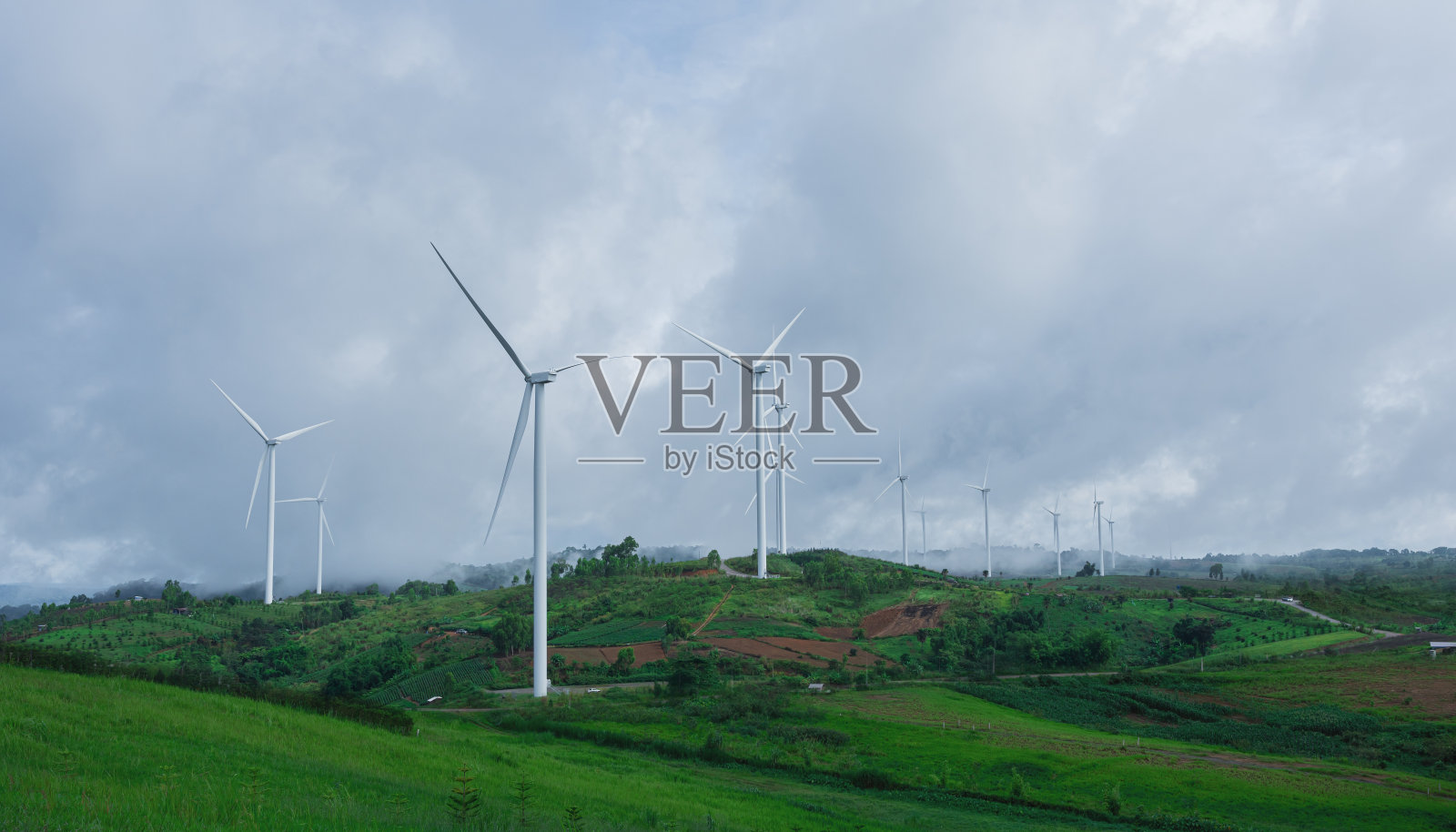 丘陵和风力涡轮机的景观与雾蒙蒙的早晨时间。照片摄影图片