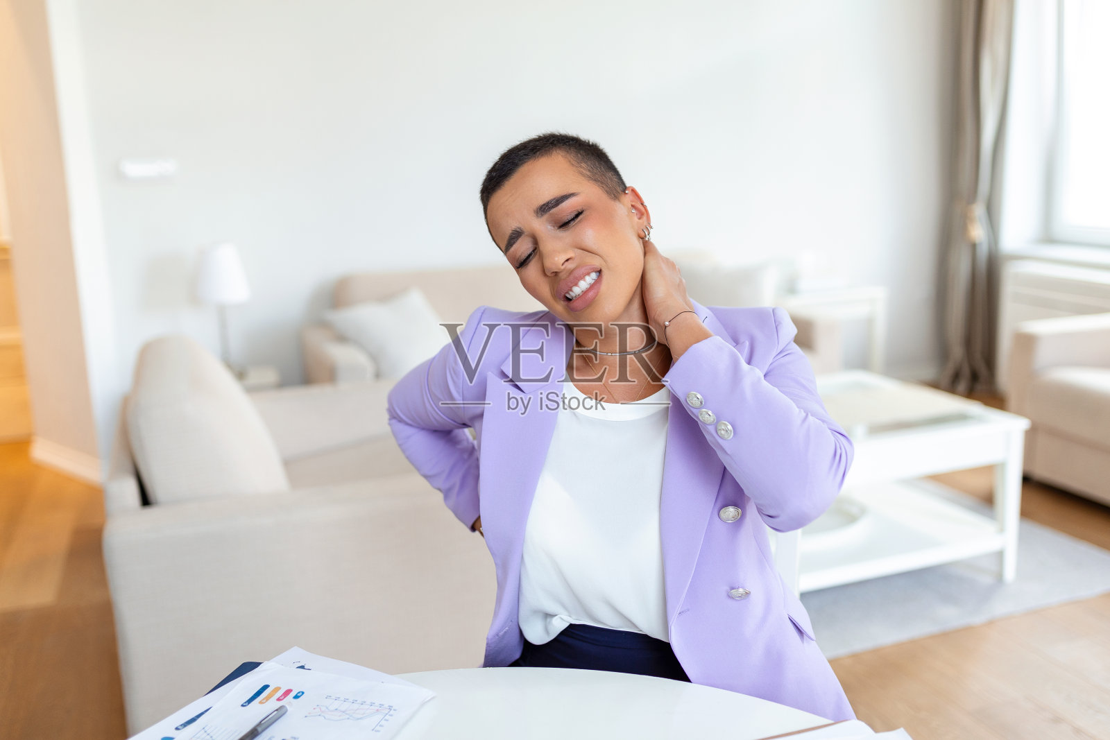 感觉筋疲力尽。沮丧的年轻女子看起来筋疲力尽，按摩她的脖子，而坐在她的工作场所照片摄影图片