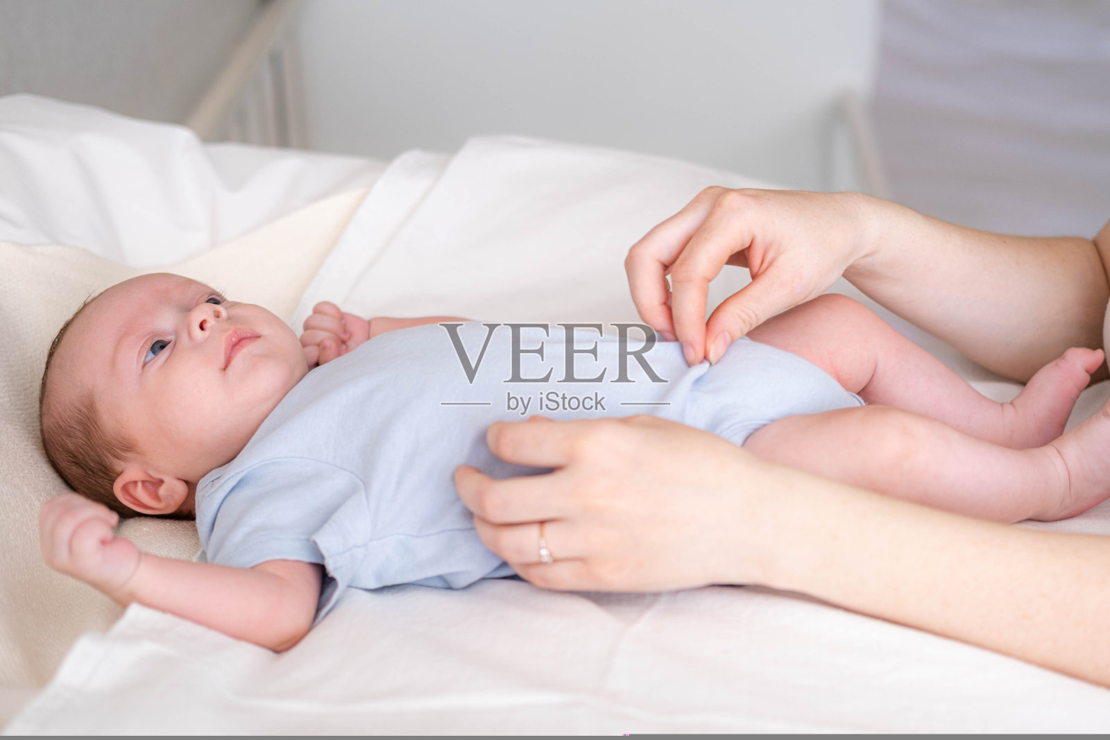 妈妈给刚出生的宝宝换尿布，小男孩在换尿布桌上换干净的干尿布，妈妈照顾婴儿，母亲的日常。照片摄影图片