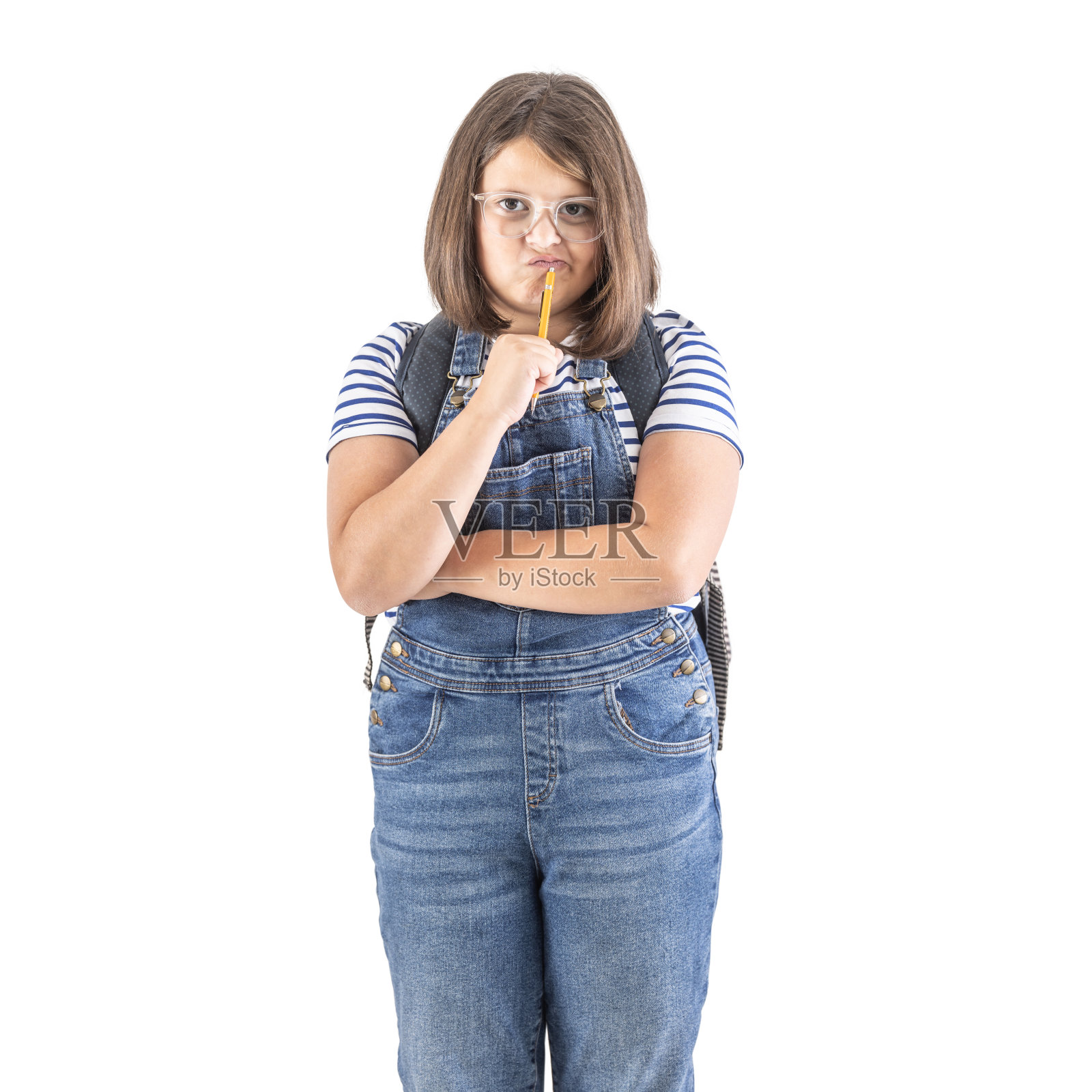 戴眼镜的女生双臂交叉，嘴里叼着铅笔，认真思考着。照片摄影图片