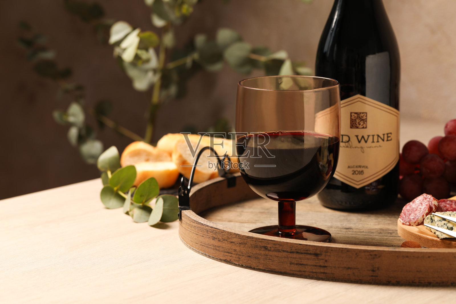 靠近酒瓶的一杯美味的红酒，木桌上的美味小吃照片摄影图片