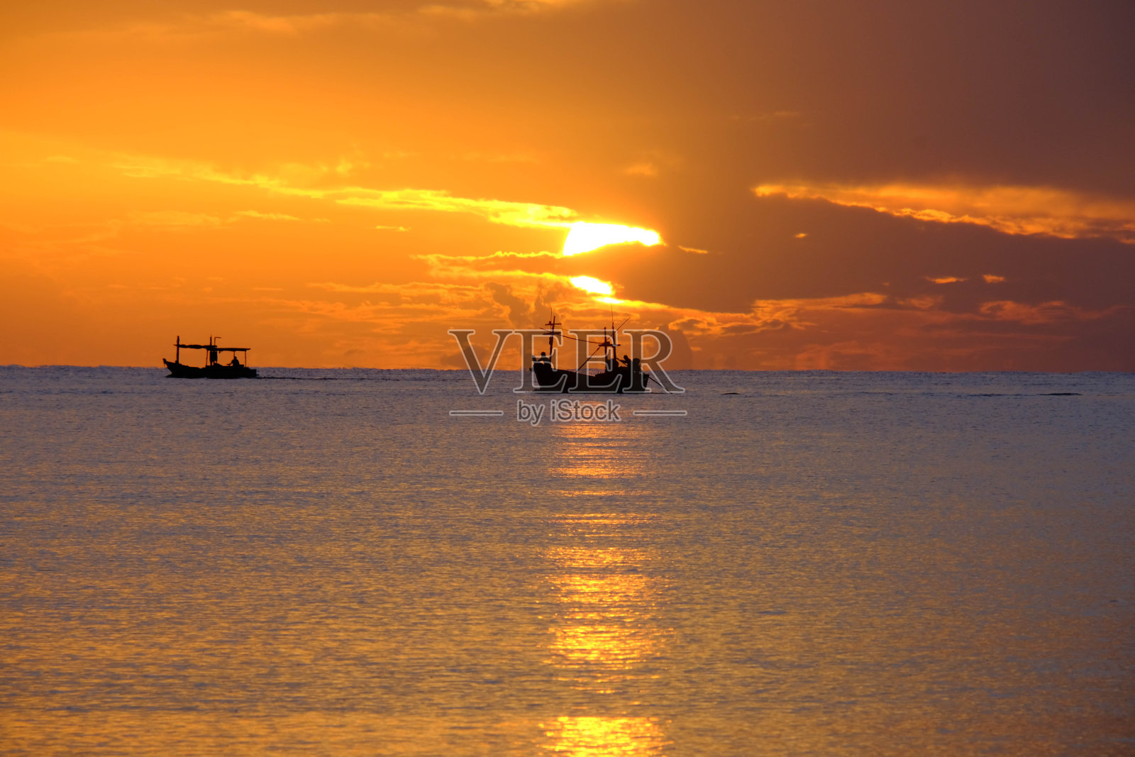 夕阳下，渔船在海面上航行的剪影，金色的光映在水面上，波浪柔和。暑假旅游理念。照片摄影图片