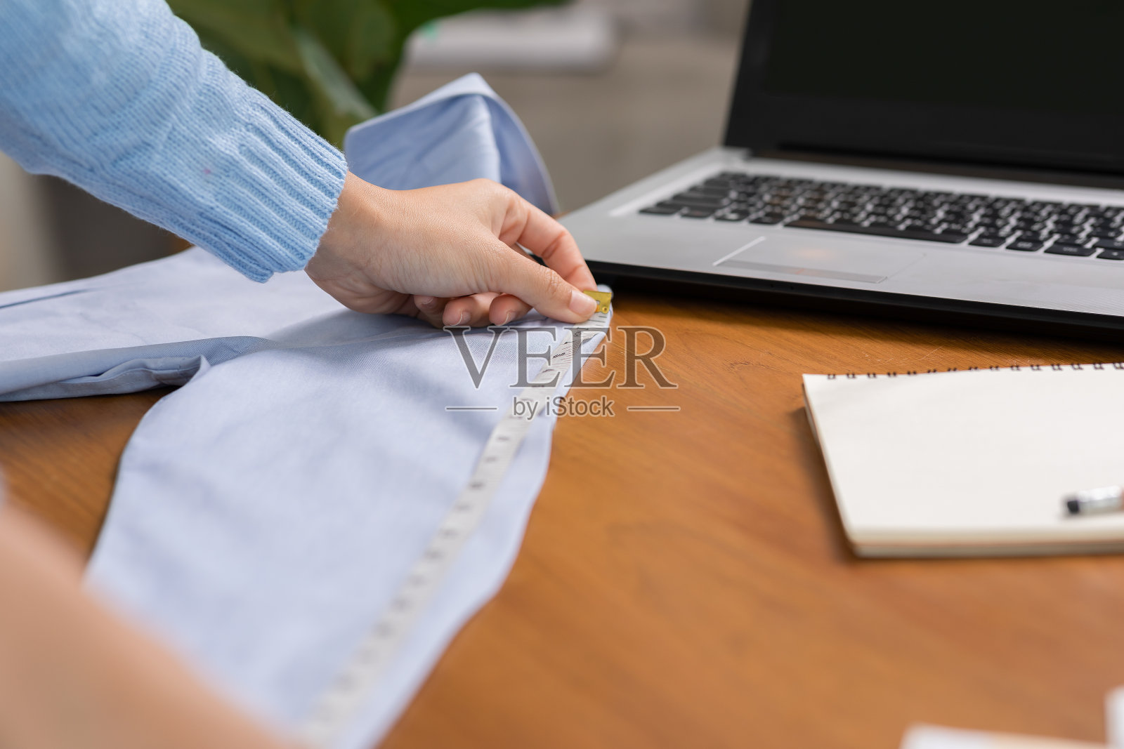 接近时尚和设计师女性工作测量与测量卷尺为新布或服装制作集合。时装设计师裁缝在她的工作室的桌子上工作。自由设计师的概念照片摄影图片