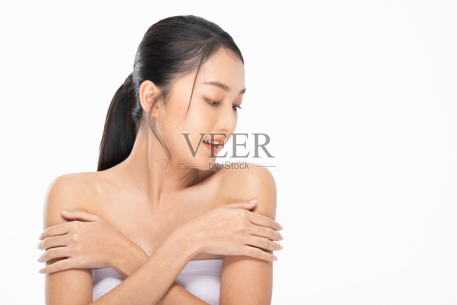 健康美丽的年轻亚洲妇女看着，触摸肩膀，感觉如此快乐和愉快的健康清洁和新鲜的皮肤，隔离在白色。自我护理和美容化妆品概念照片摄影图片