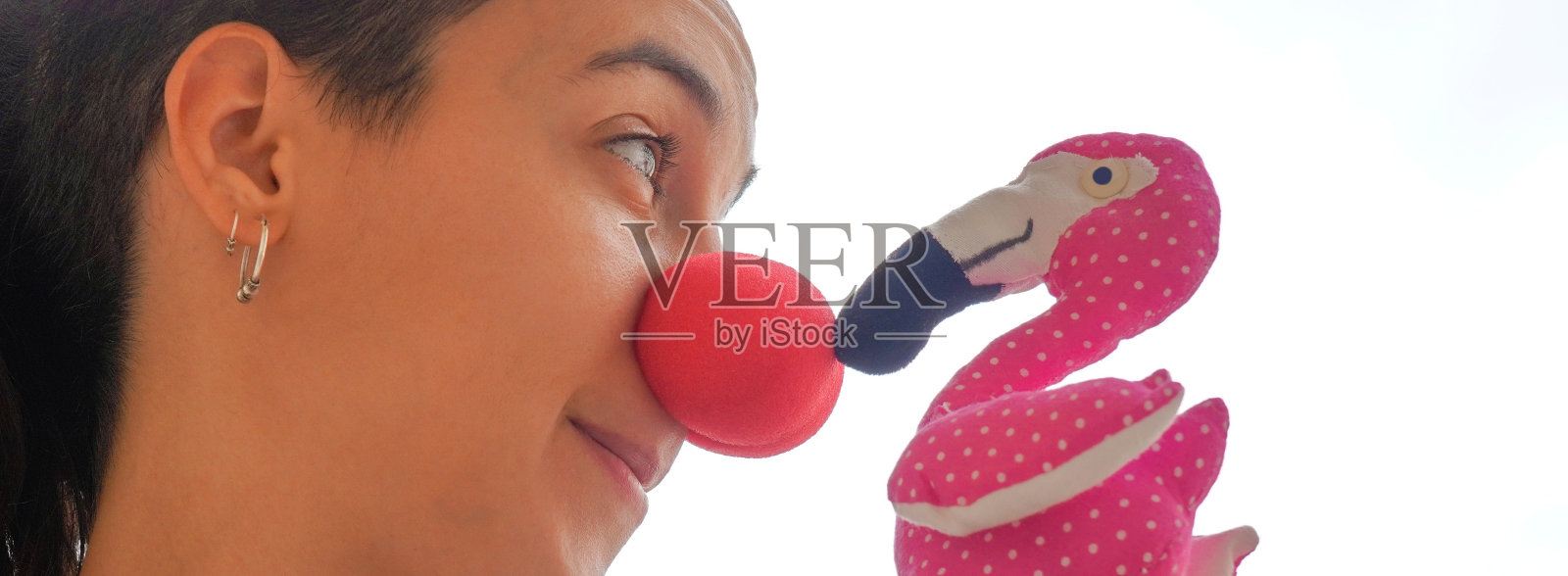 红鼻子的女小丑看着一只火烈鸟标本。前景照片摄影图片